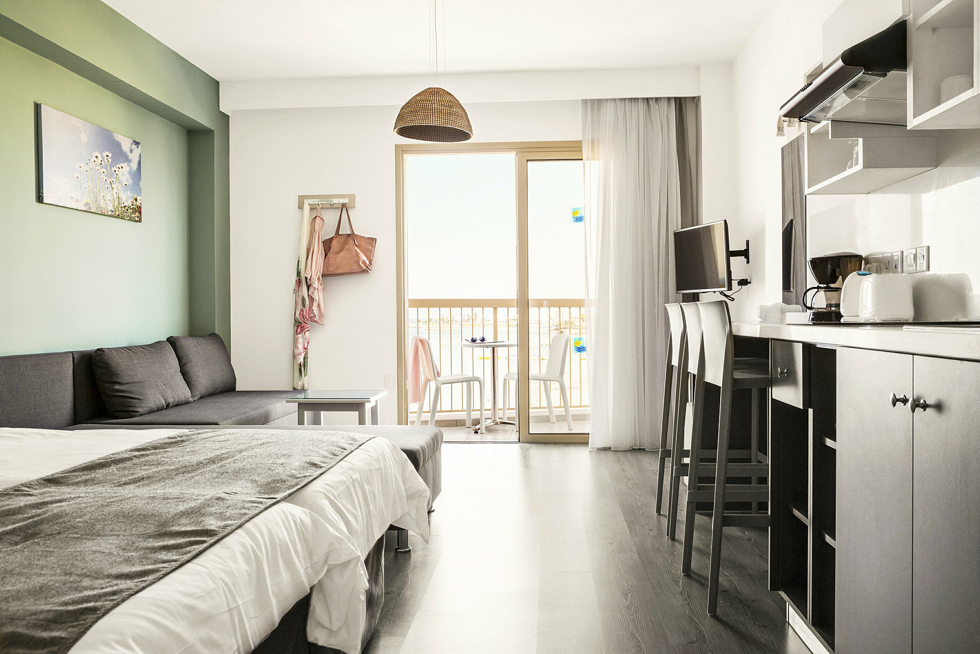 Et moderne hotelværelse med sovesofa, seng, køkkenudstyr og altan med udsigt. (AI-genereret tekst)