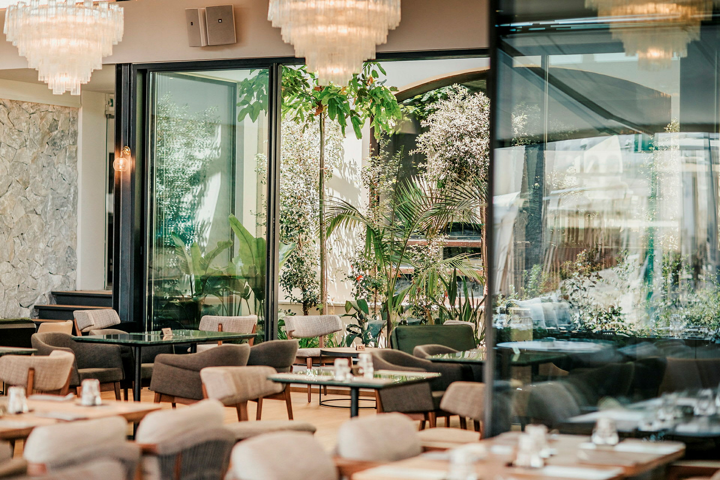 En moderne, lyst restaurant med store vinduer og grønne områder udenfor. (AI-genereret tekst)