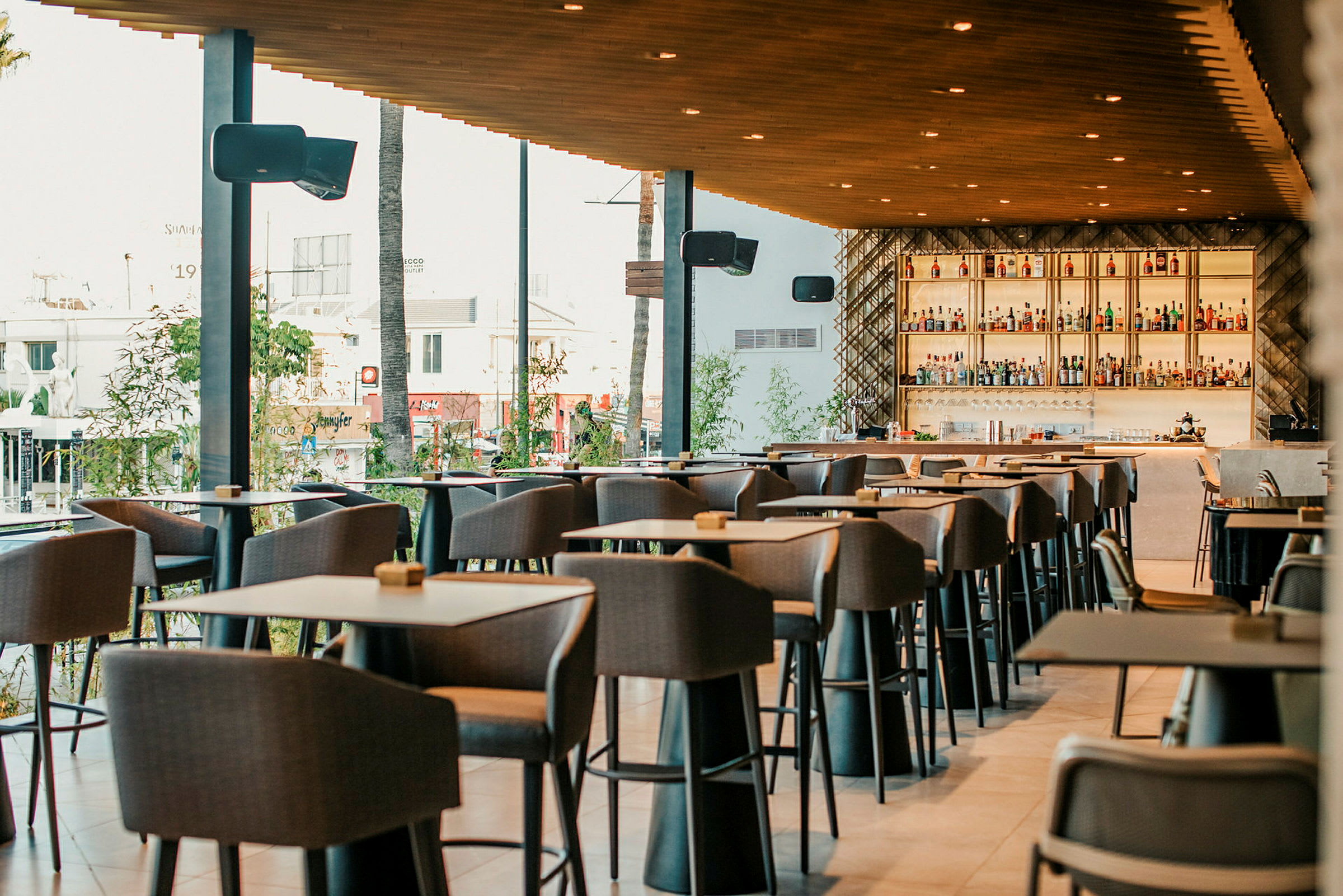 Billede af en moderne restaurant med høje borde og stole samt en veludstyret bar i baggrunden. (AI-genereret tekst)