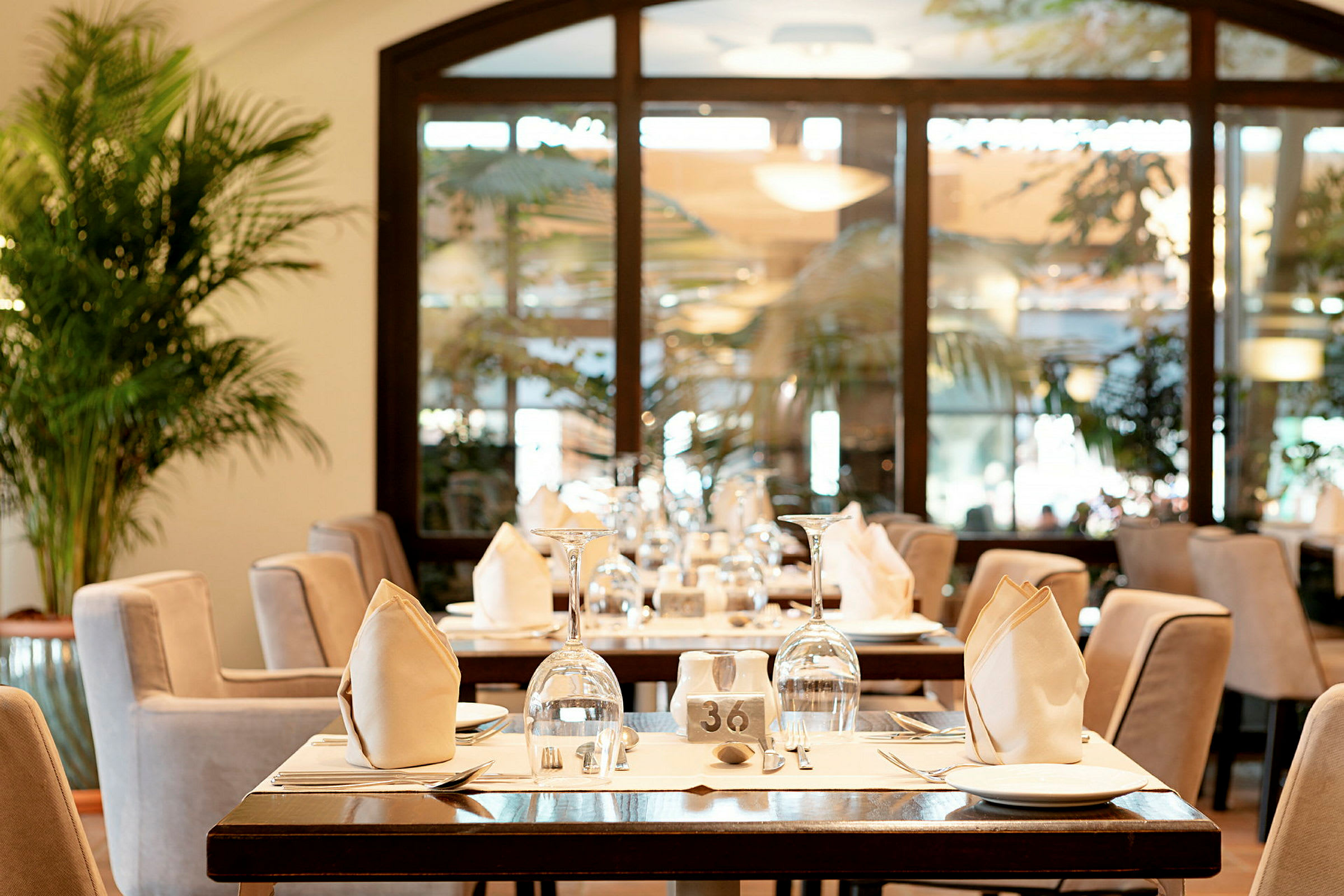 Et restaurantbord med elegant borddækning, herunder glas, tallerkener og foldede servietter. (AI-genereret tekst)