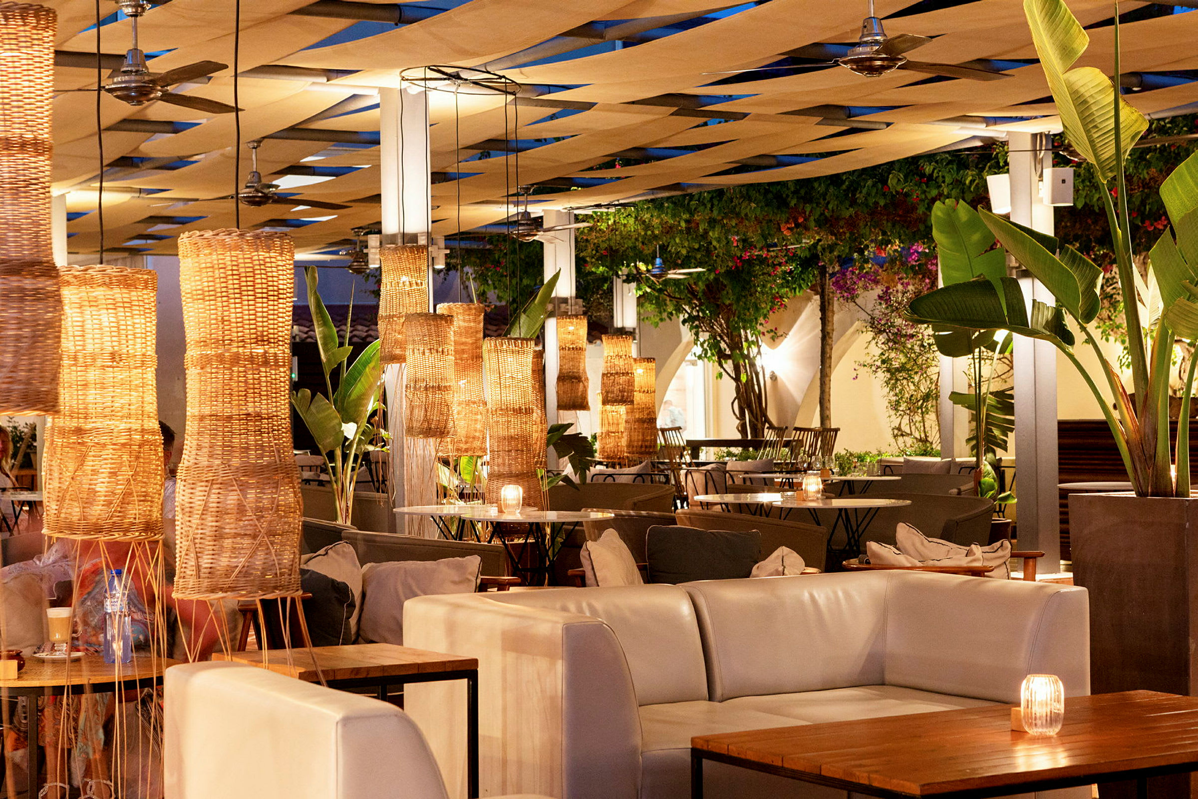 En udendørs restaurant med lysdekorationer i kurvelamper og planteindretning. (AI-genereret tekst)