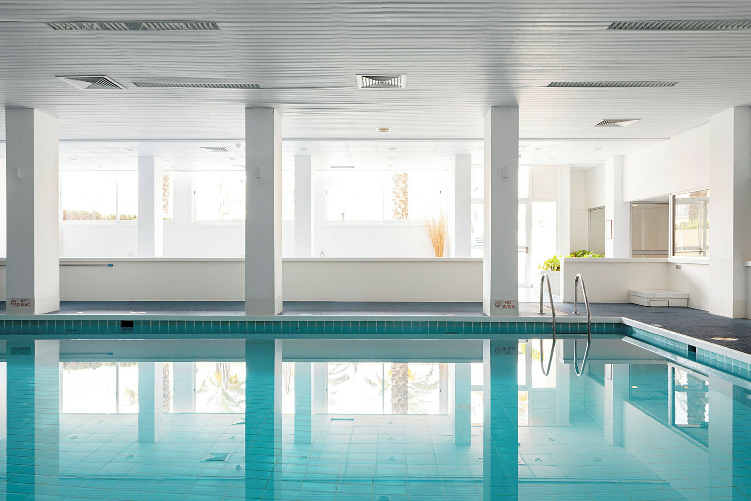 Indendørs pool med klart vand og lyse vægge. (AI-genereret tekst)