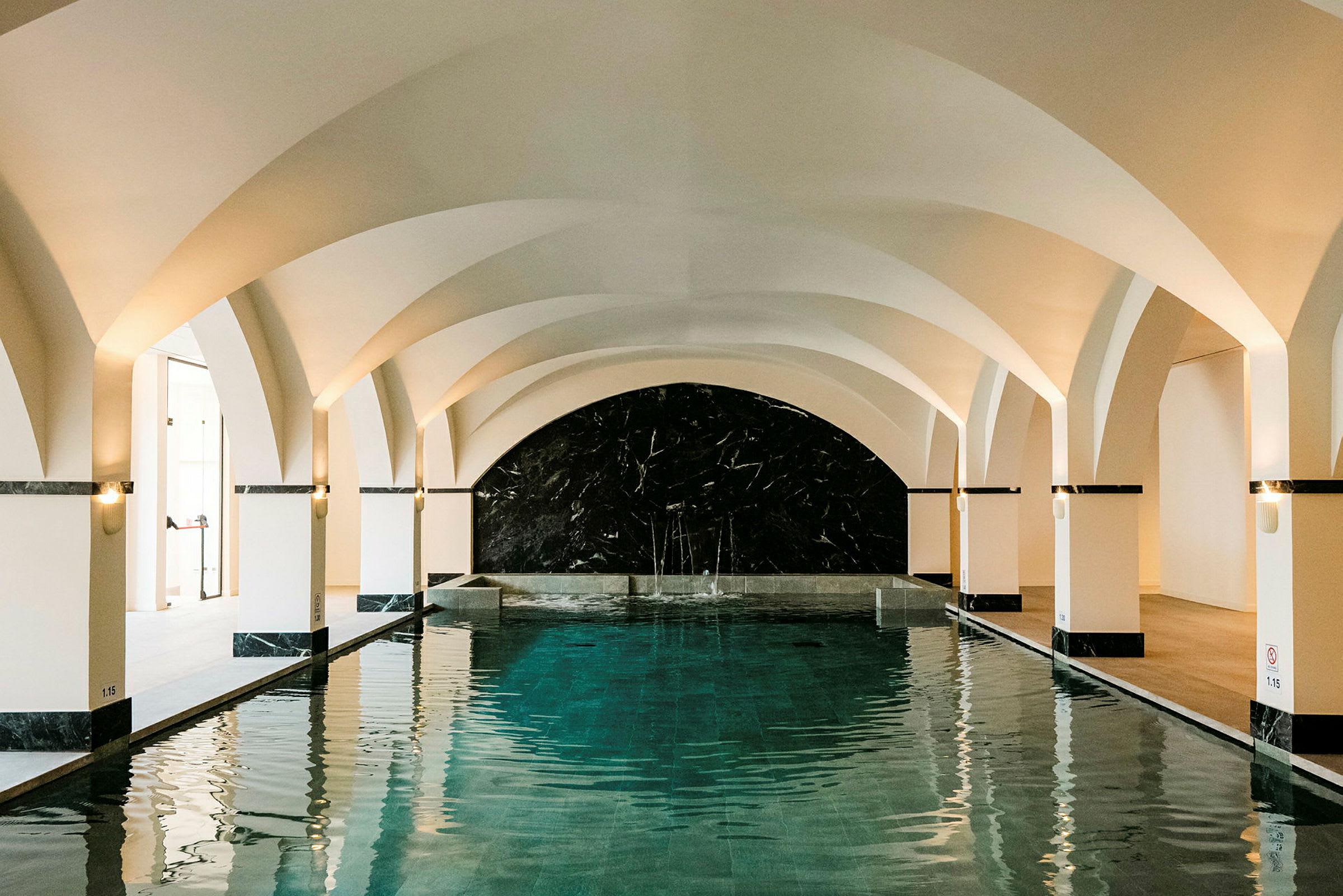 En indendørs pool med hvælvede lofter og marmordetaljer. (AI-genereret tekst)
