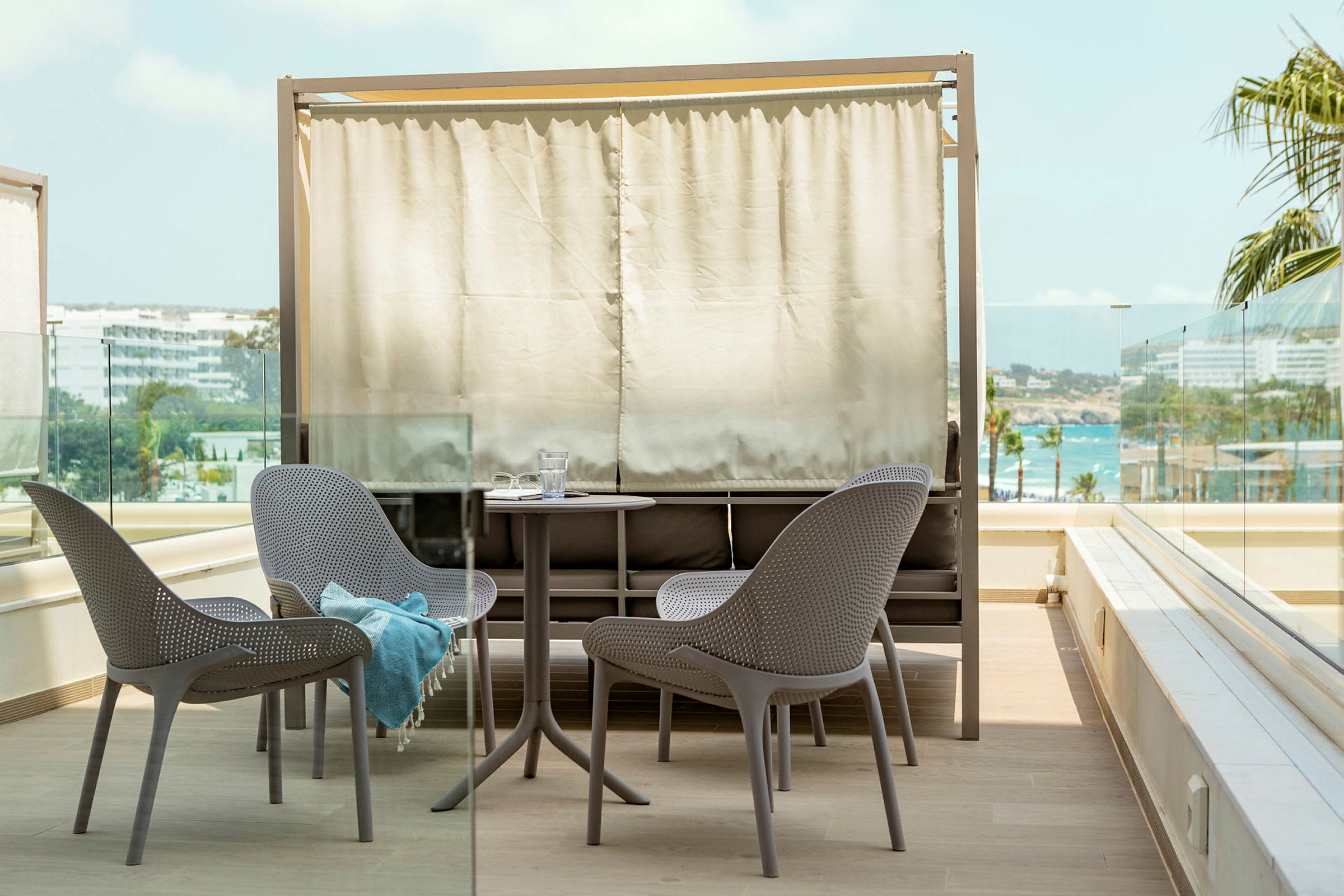 Terrasse med bord og stole, skærmmøbel i baggrunden. (AI-genereret tekst)