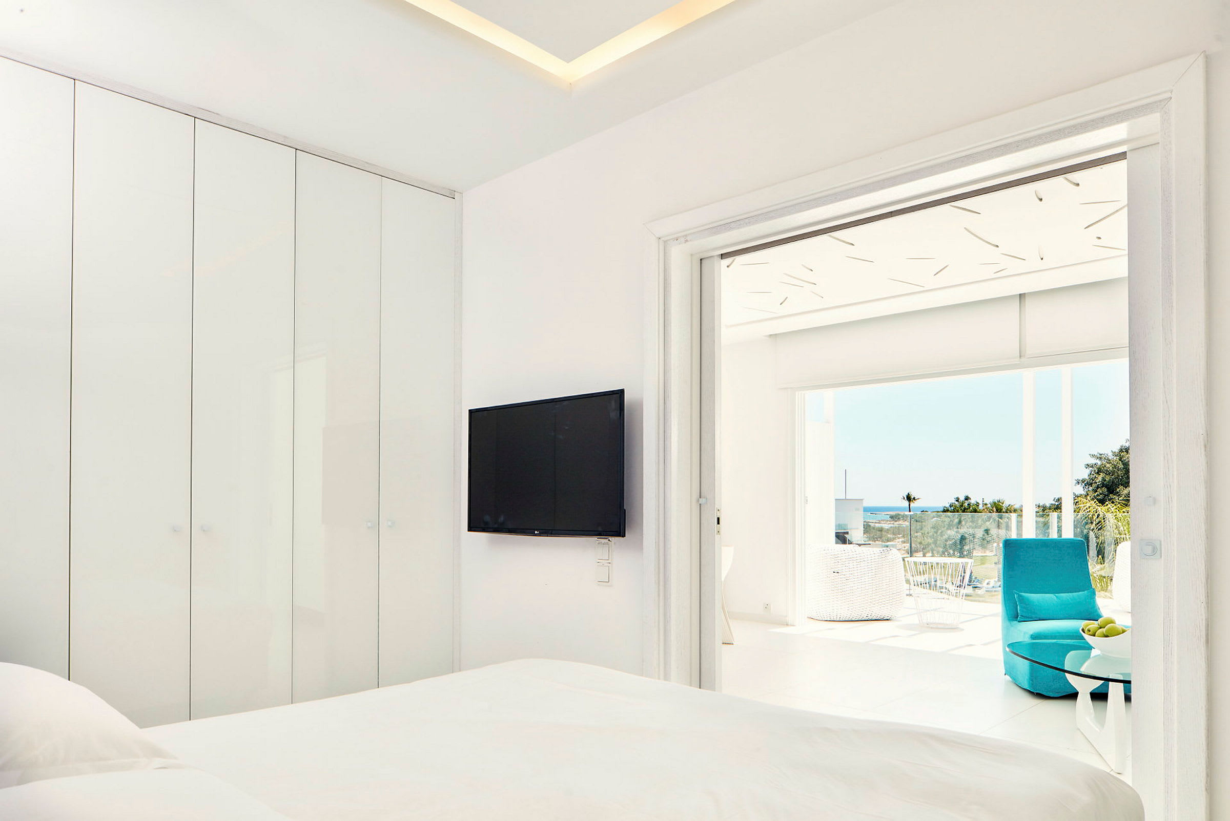 Moderne hotelværelse med fladskærms-tv og tilhørende balkon med udsigt. (AI-genereret tekst)