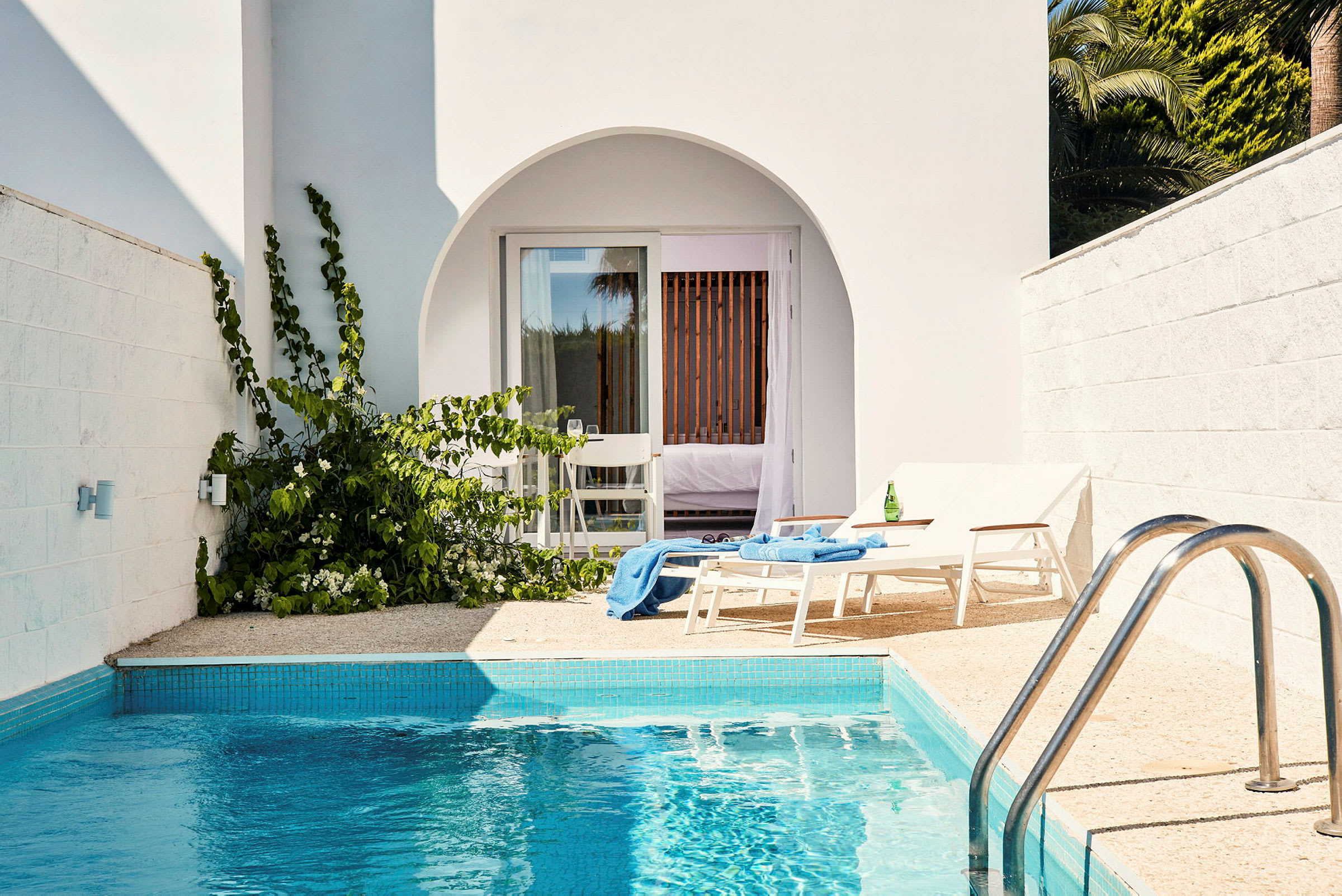 Privat terrasse med pool, to liggestole og tilhørende hotelværelse ses. (AI-genereret tekst)