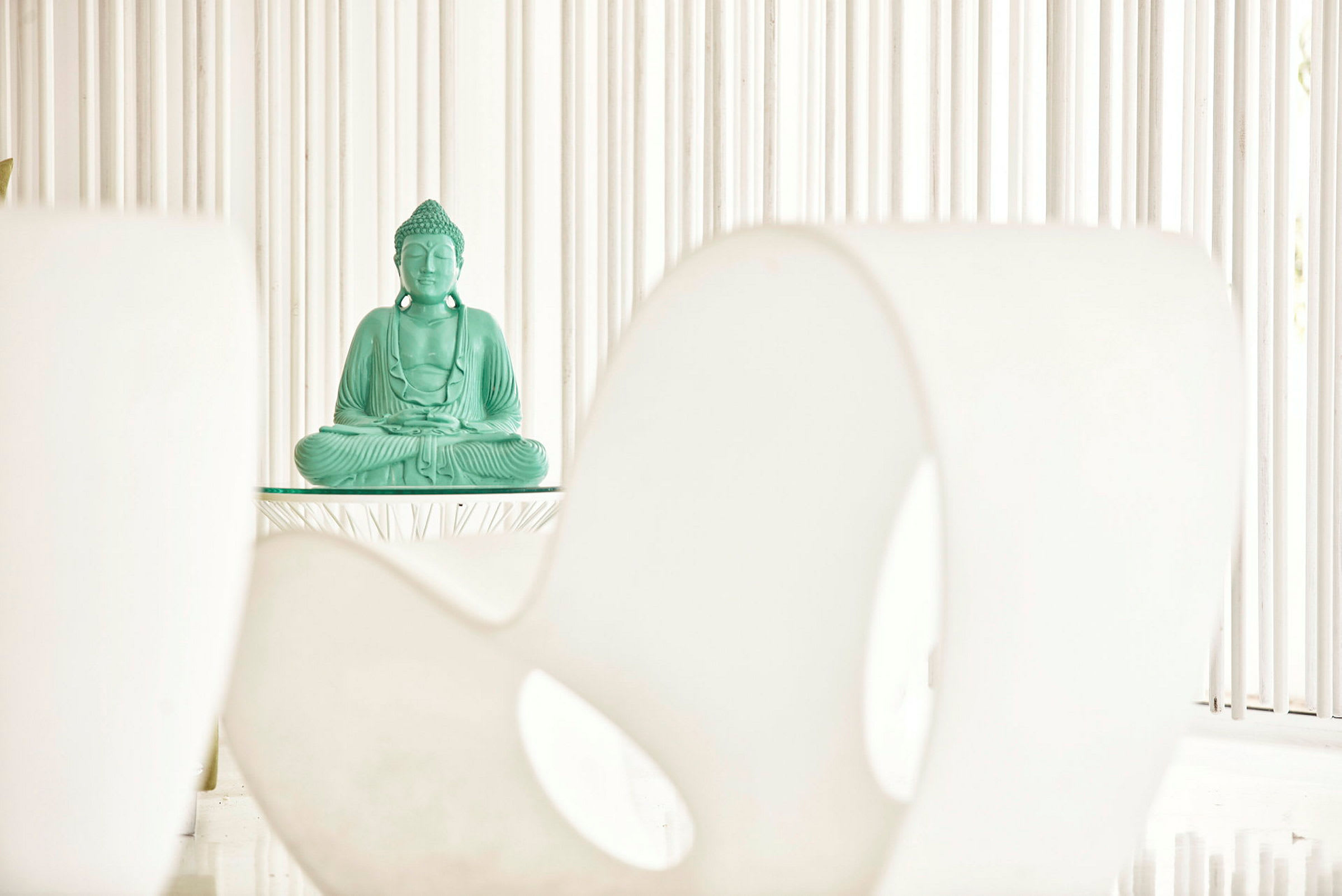 En grøn Buddha-statue placeret på et bord mod en minimalistisk baggrund. (AI-genereret tekst)