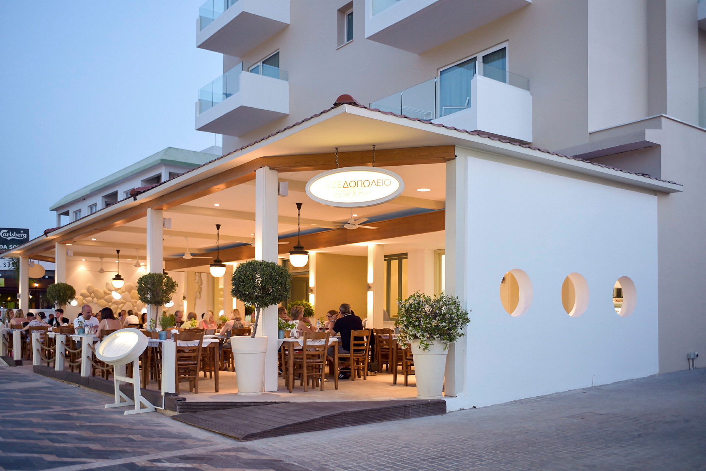 Udendørs terrasse med siddepladser på en restaurant ved siden af en bygning. (AI-genereret tekst)