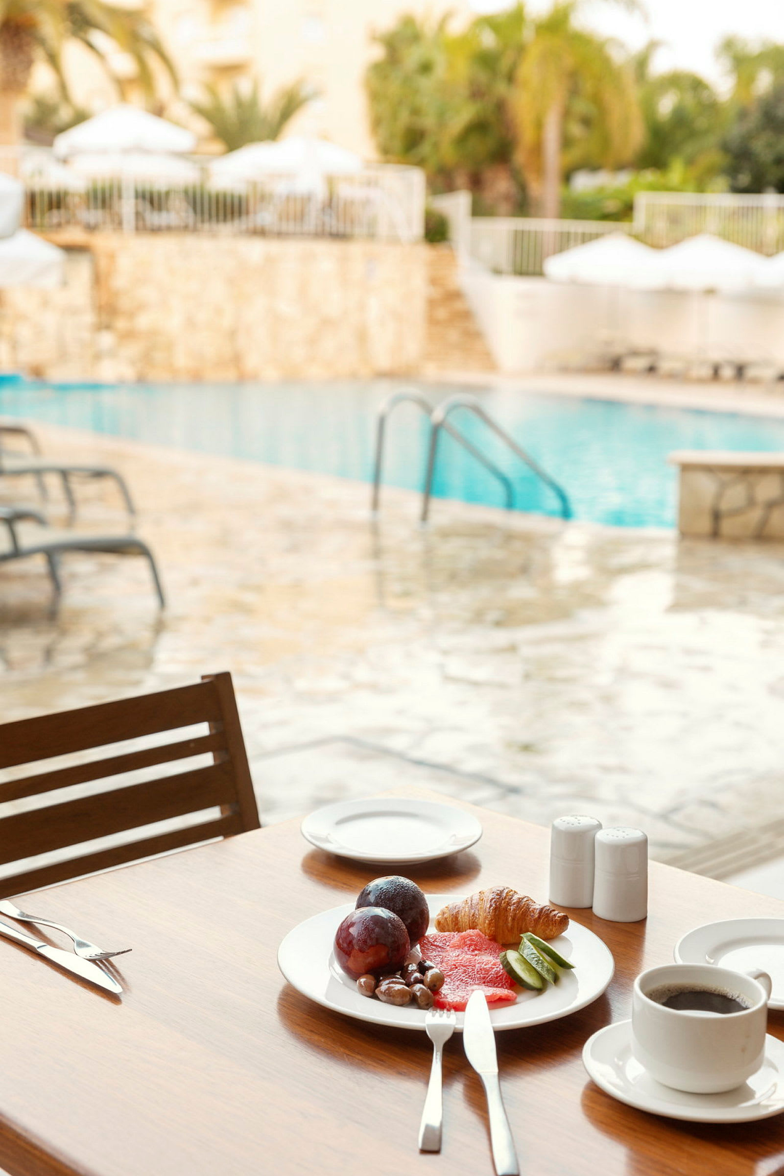 Morgenmad med kaffe og frugt ved en pool. (AI-genereret tekst)