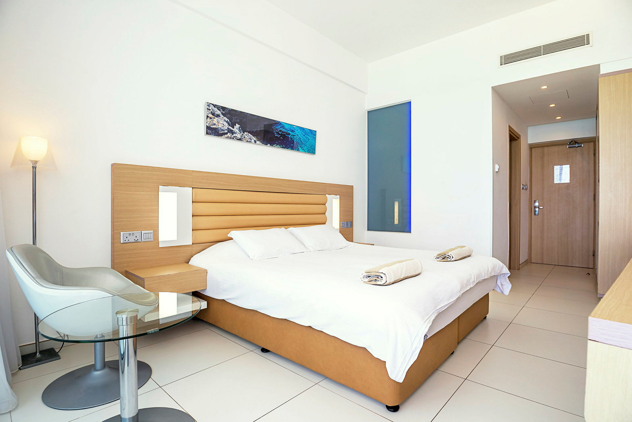 Moderne hotelværelse med dobbeltseng, stol og bord. (AI-genereret tekst)