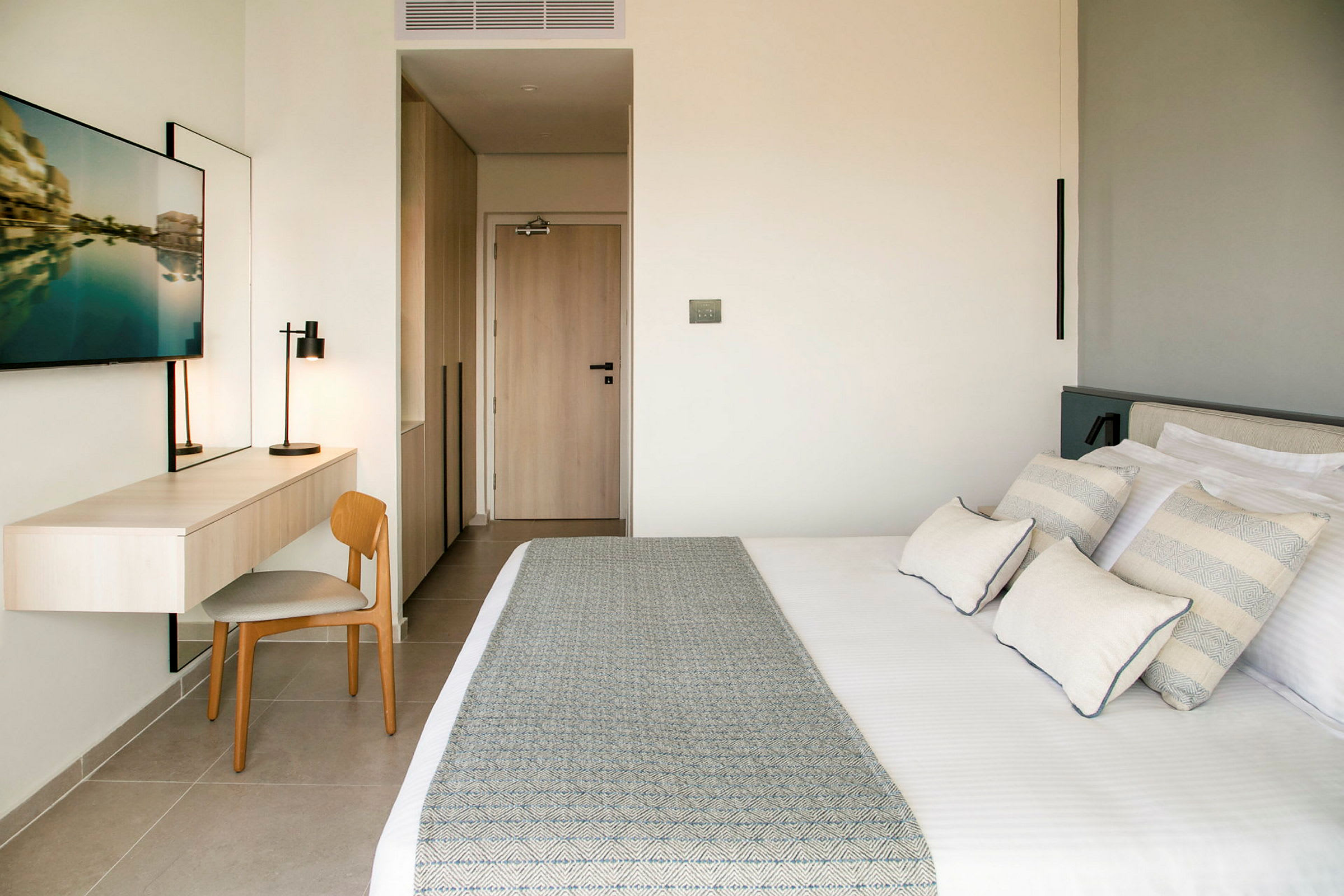 Moderne hotelværelse med seng, skrivebord, stol og tv. (AI-genereret tekst)