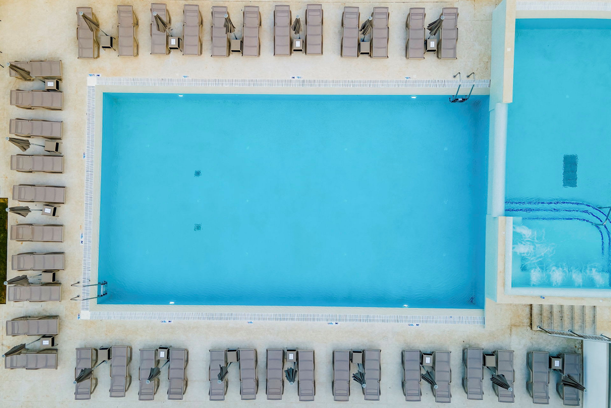 Udendørs swimmingpool omgivet af liggestole set ovenfra. (AI-genereret tekst)