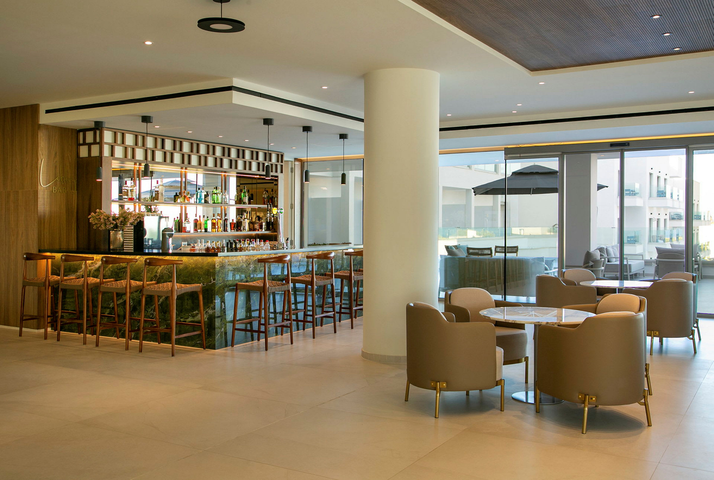Billede af en moderne hotelbar med barstole og siddegrupper. (AI-genereret tekst)