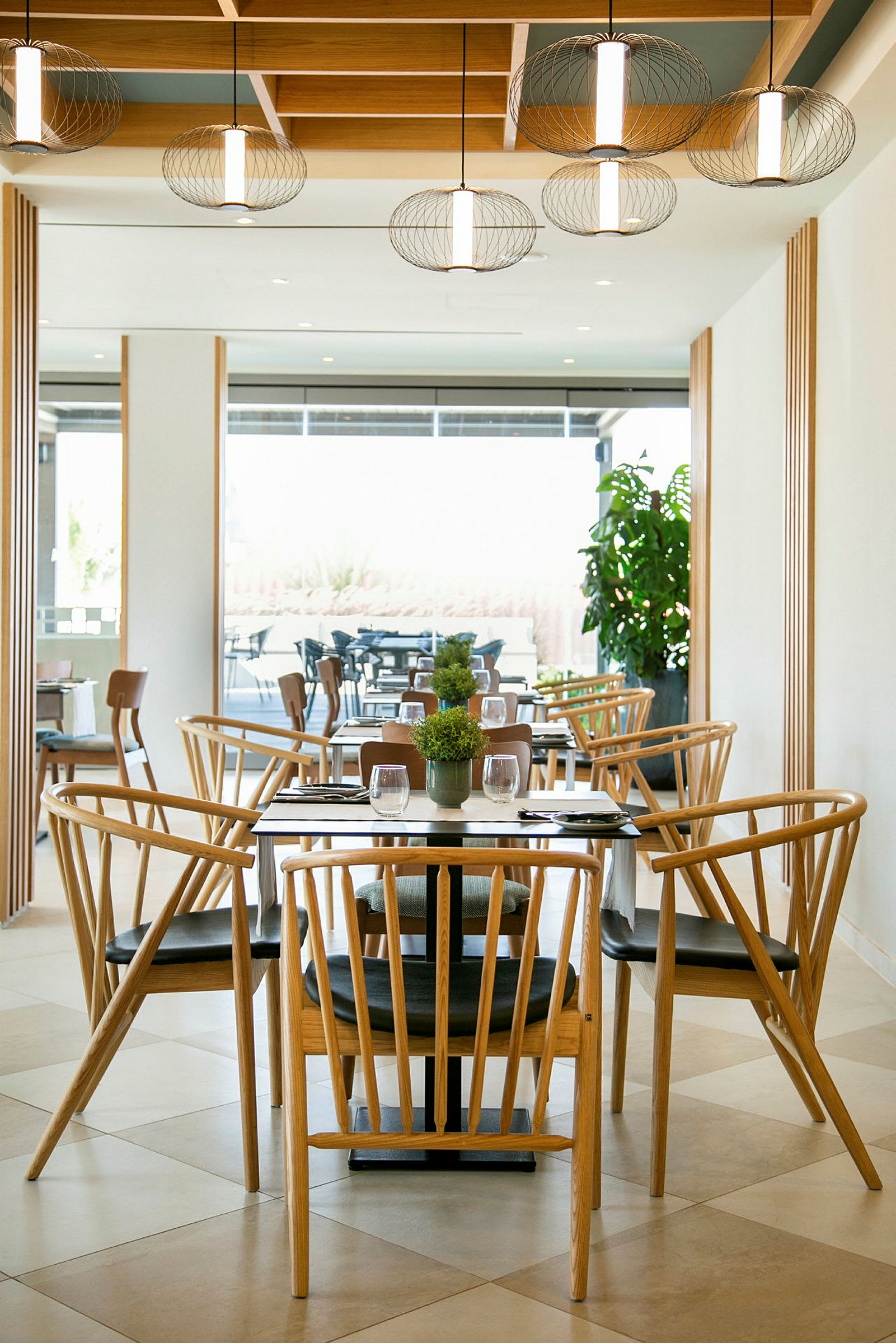 En restaurant med træstole og borde samt dekorative lamper i loftet. (AI-genereret tekst)