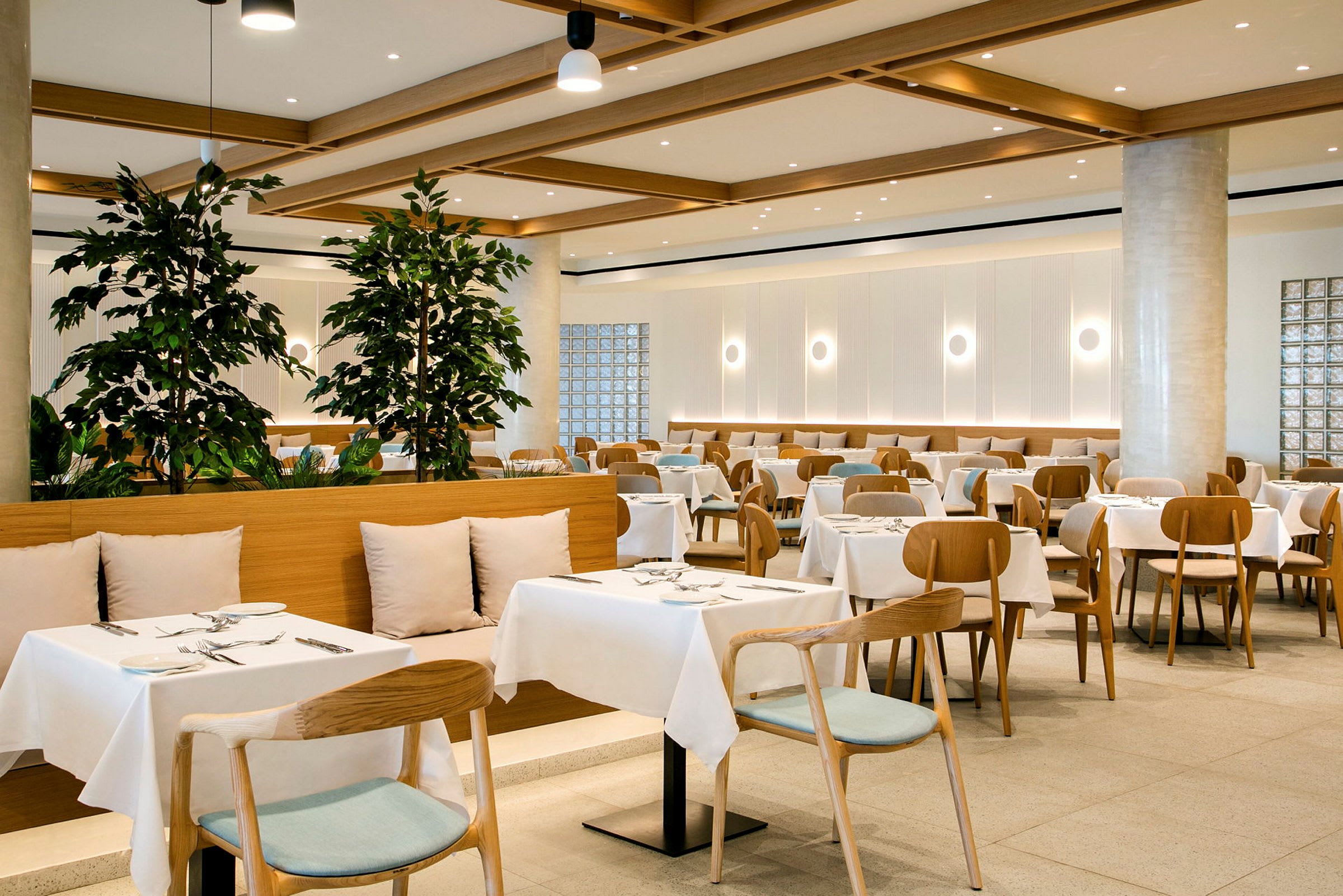 En moderne restaurant med oprettede borde og stole, dekoreret med grønne planter. (AI-genereret tekst)