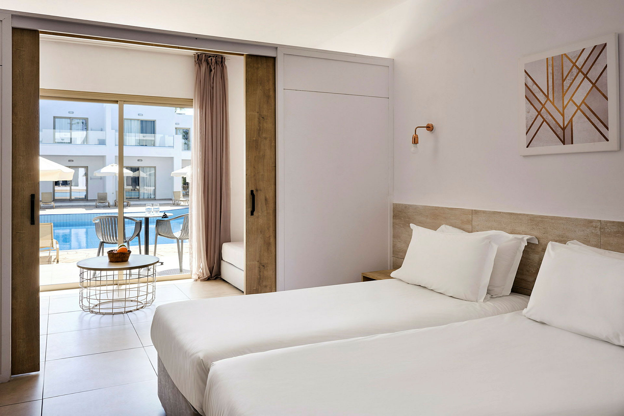 Hotelværelse med to enkeltsenge og udsigt til en udendørs pool og liggestole. (AI-genereret tekst)