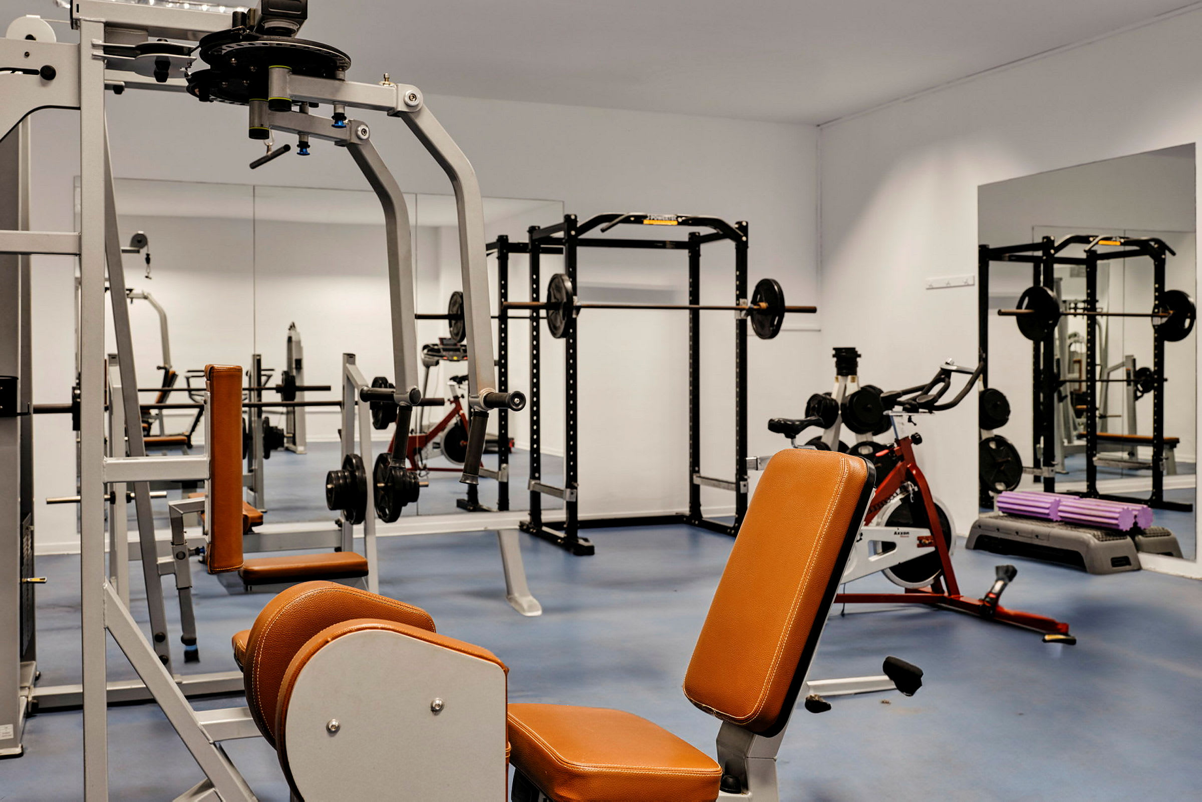Billede af et fitnesscenter med træningsmaskiner og spejle. (AI-genereret tekst)
