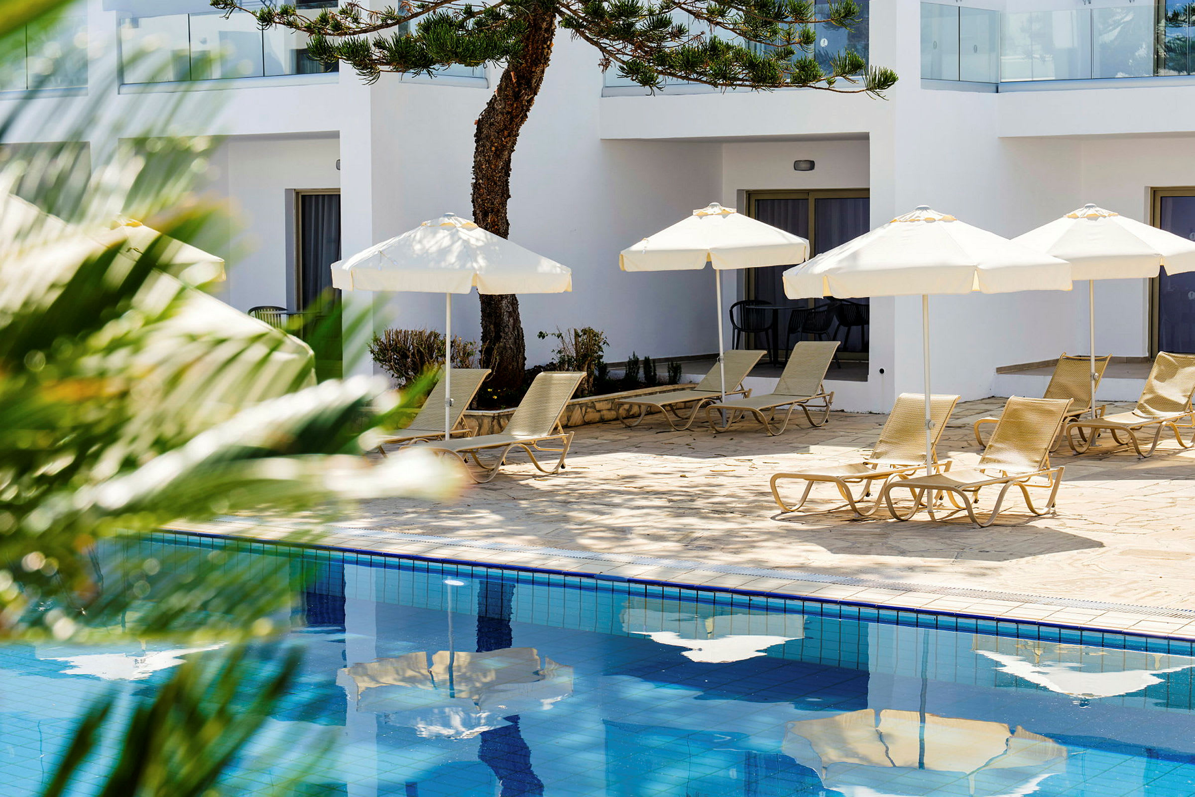 Solsenge og parasoller ved en pool med vand. (AI-genereret tekst)