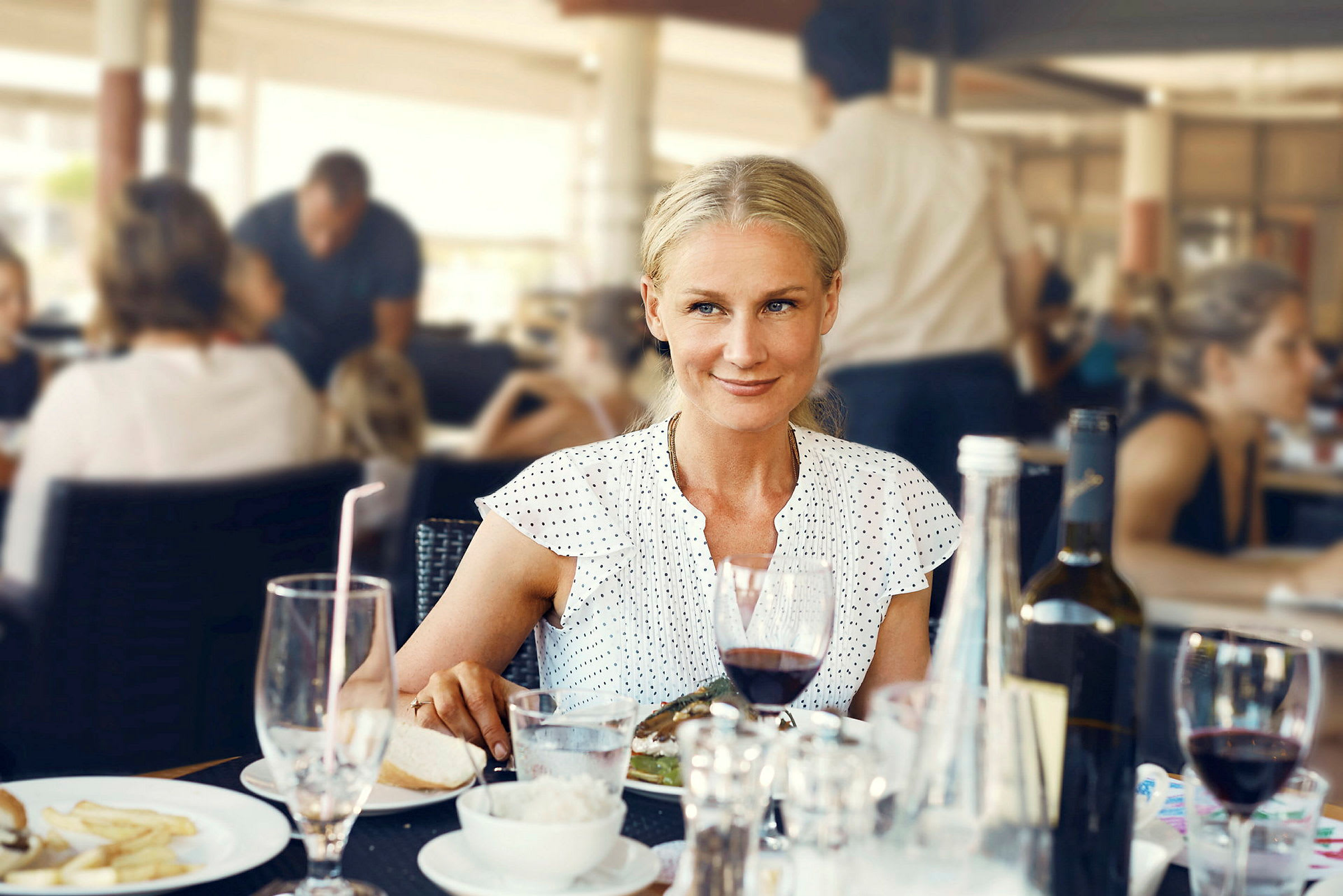 En person sidder ved et bord på en restaurant med forskellige drikkevarer og mad serveret. (AI-genereret tekst)