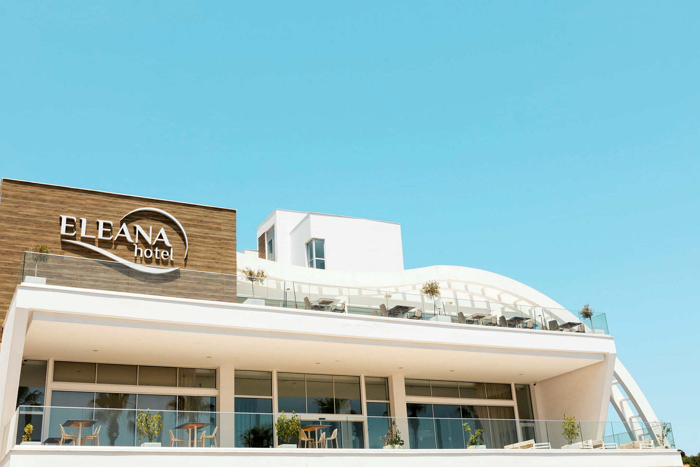Moderne hotel med navnet Eleana Hotel synligt på facaden. (AI-genereret tekst)