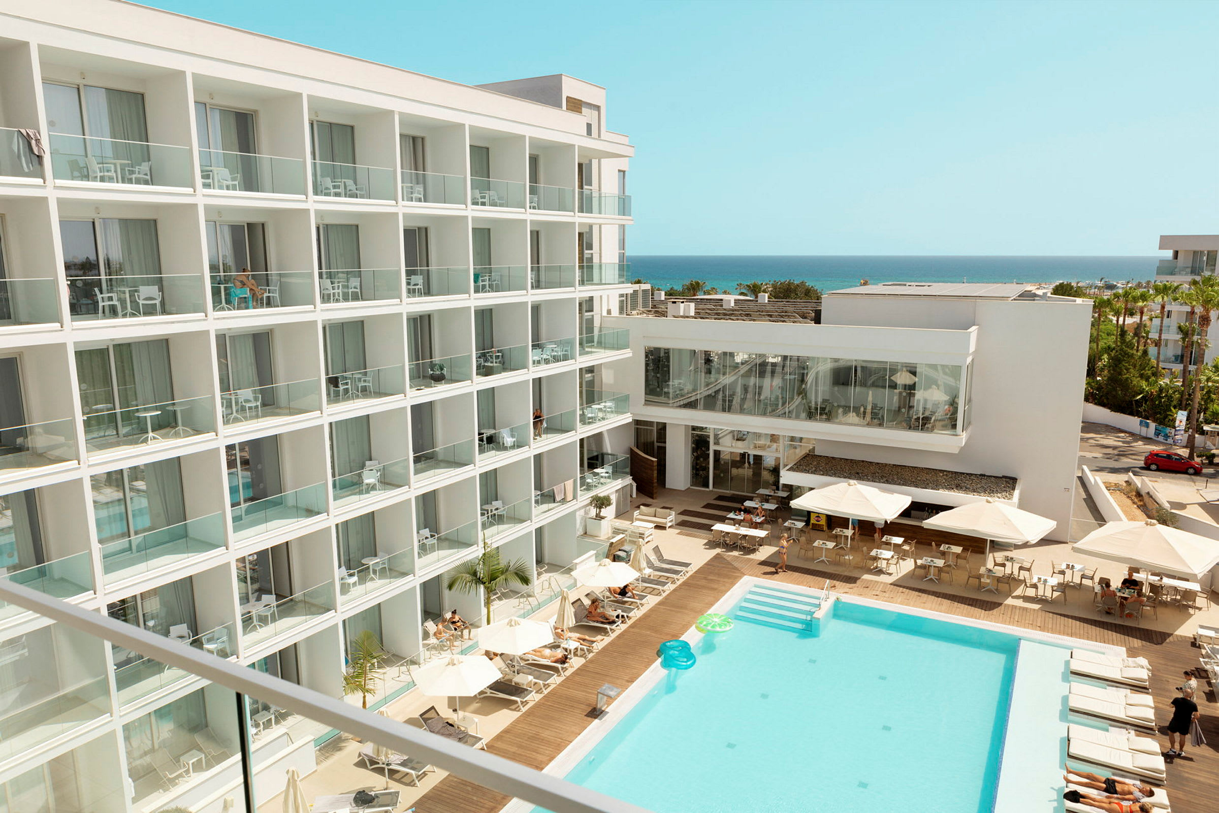 Hotel med poolområde og udsigt mod havet. (AI-genereret tekst)