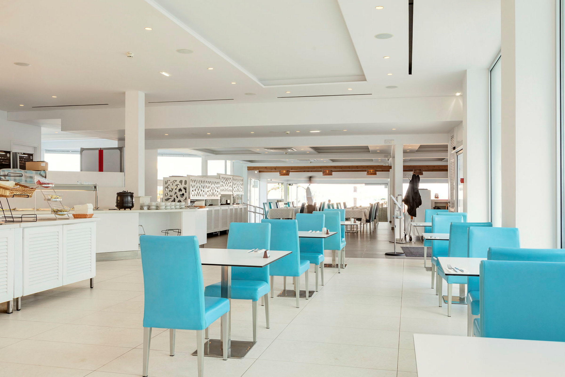 Billede af en moderne restaurant med blå stole og hvid indretning. (AI-genereret tekst)