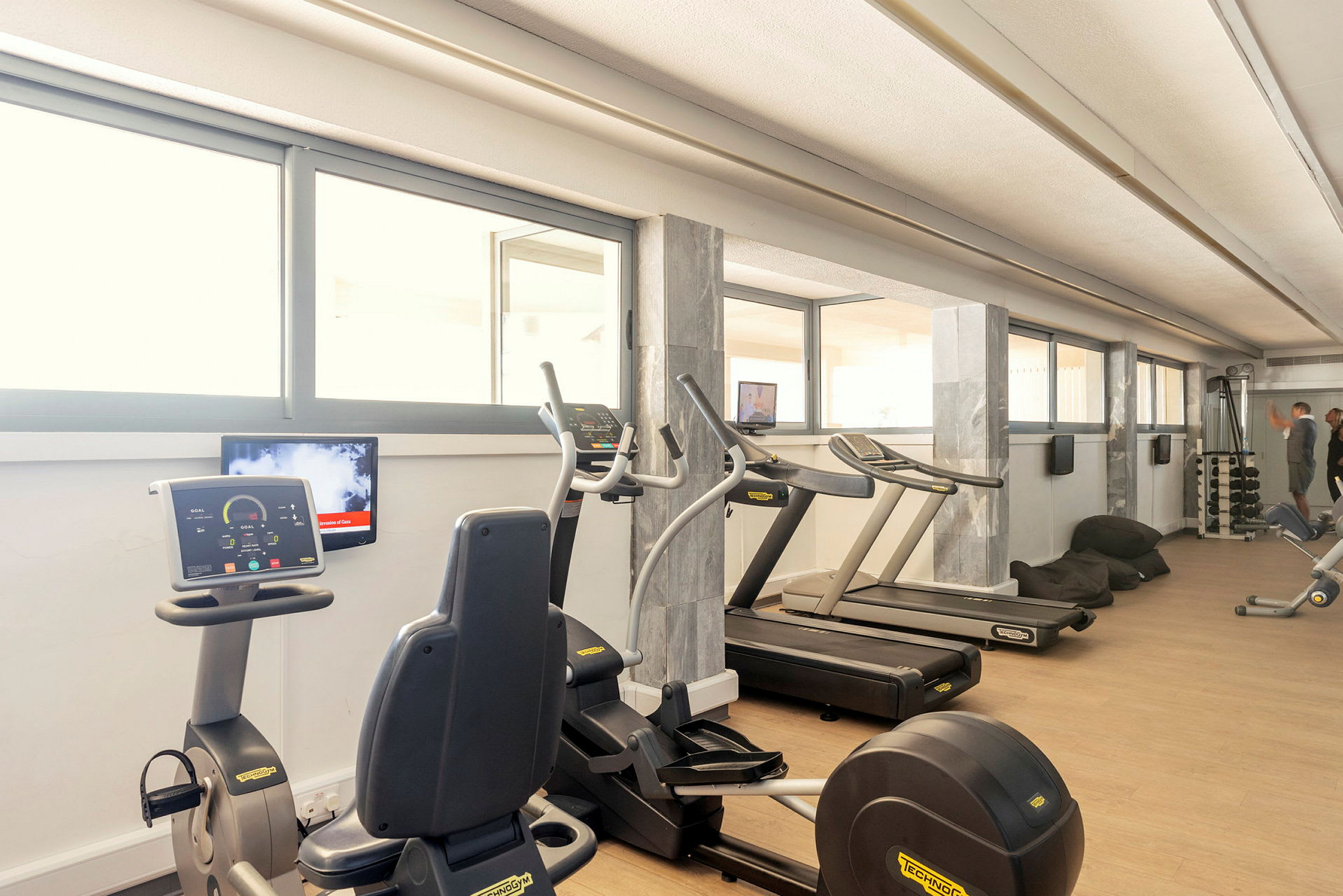 Et fitnesscenter med træningsmaskiner og store vinduer. (AI-genereret tekst)