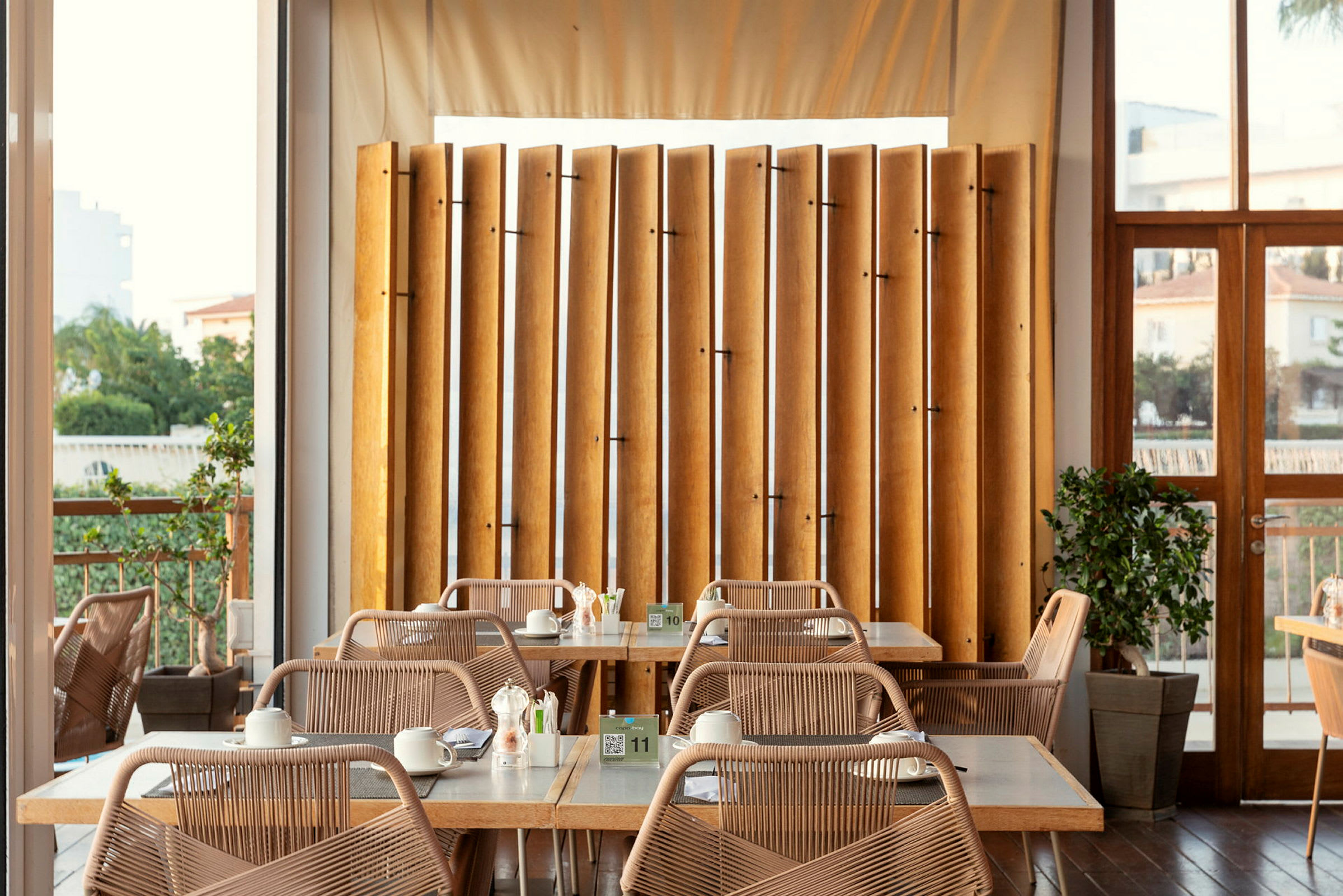 En lys restaurant med borde og stole samt vandrette placerede træer. (AI-genereret tekst)