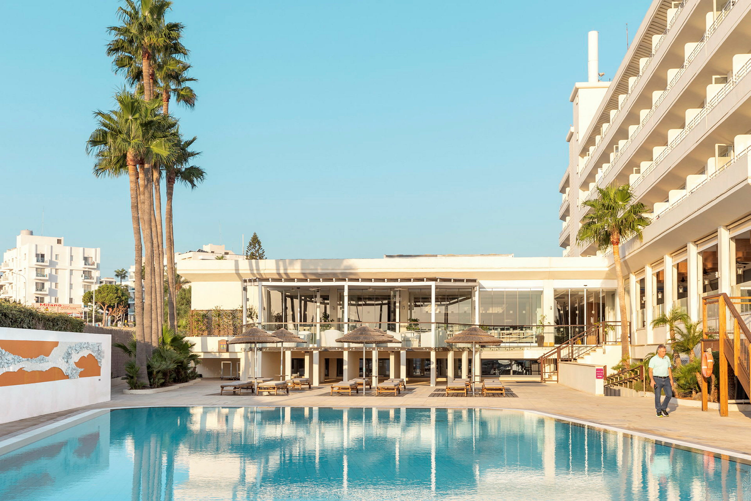 Poolområde ved hotel med liggestole og parasoller. (AI-genereret tekst)