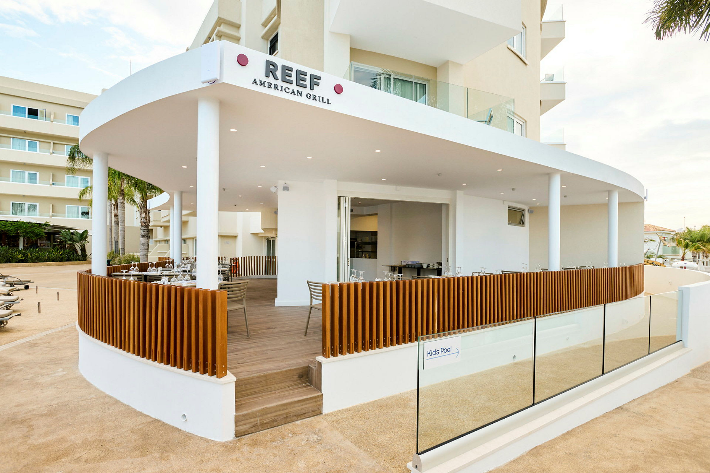 Billede af en restaurant, Reef American Grill, med en åben terrasse og moderne design. (AI-genereret tekst)