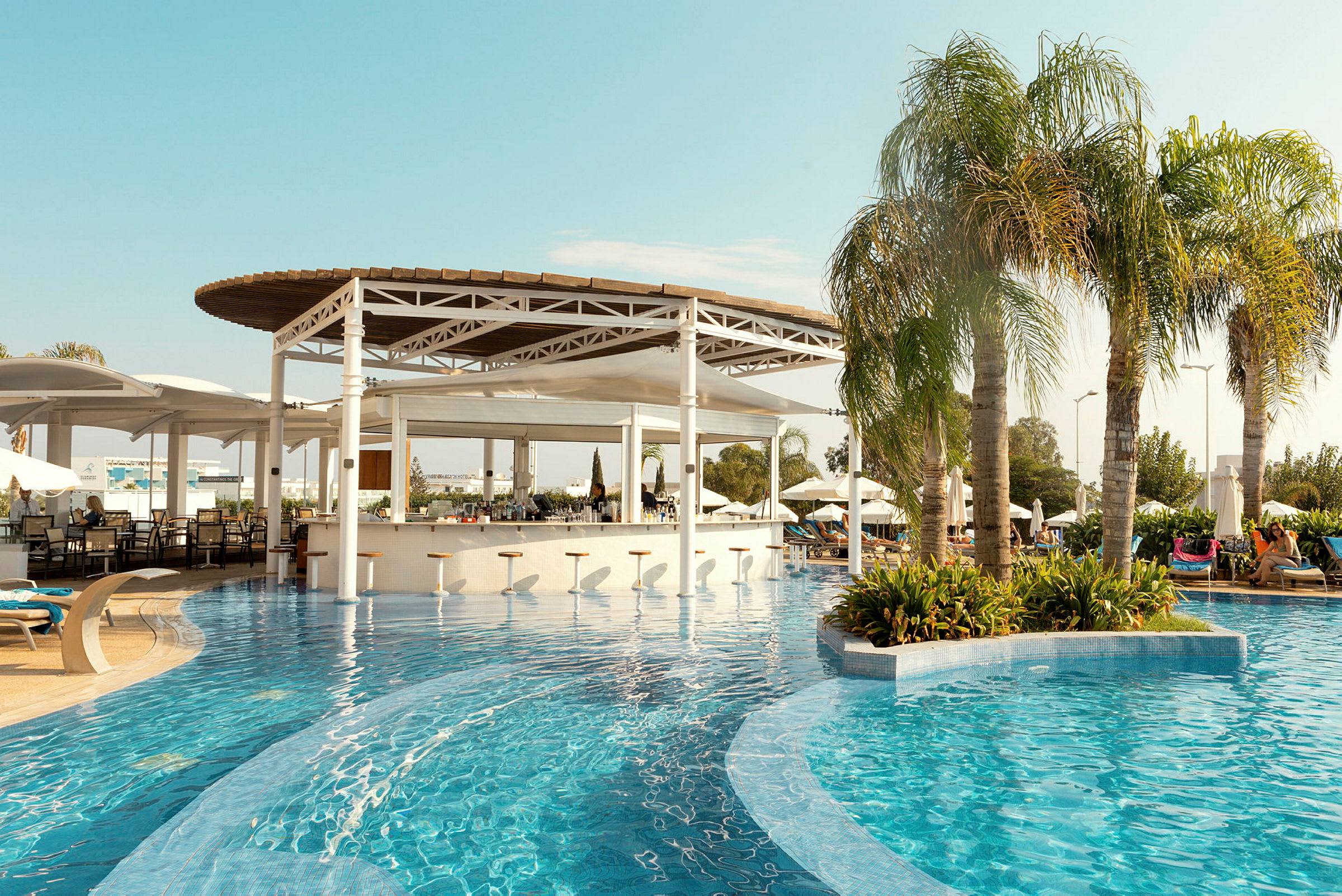 En swimmingpool med en poolbar og parasoller i baggrunden. (AI-genereret tekst)