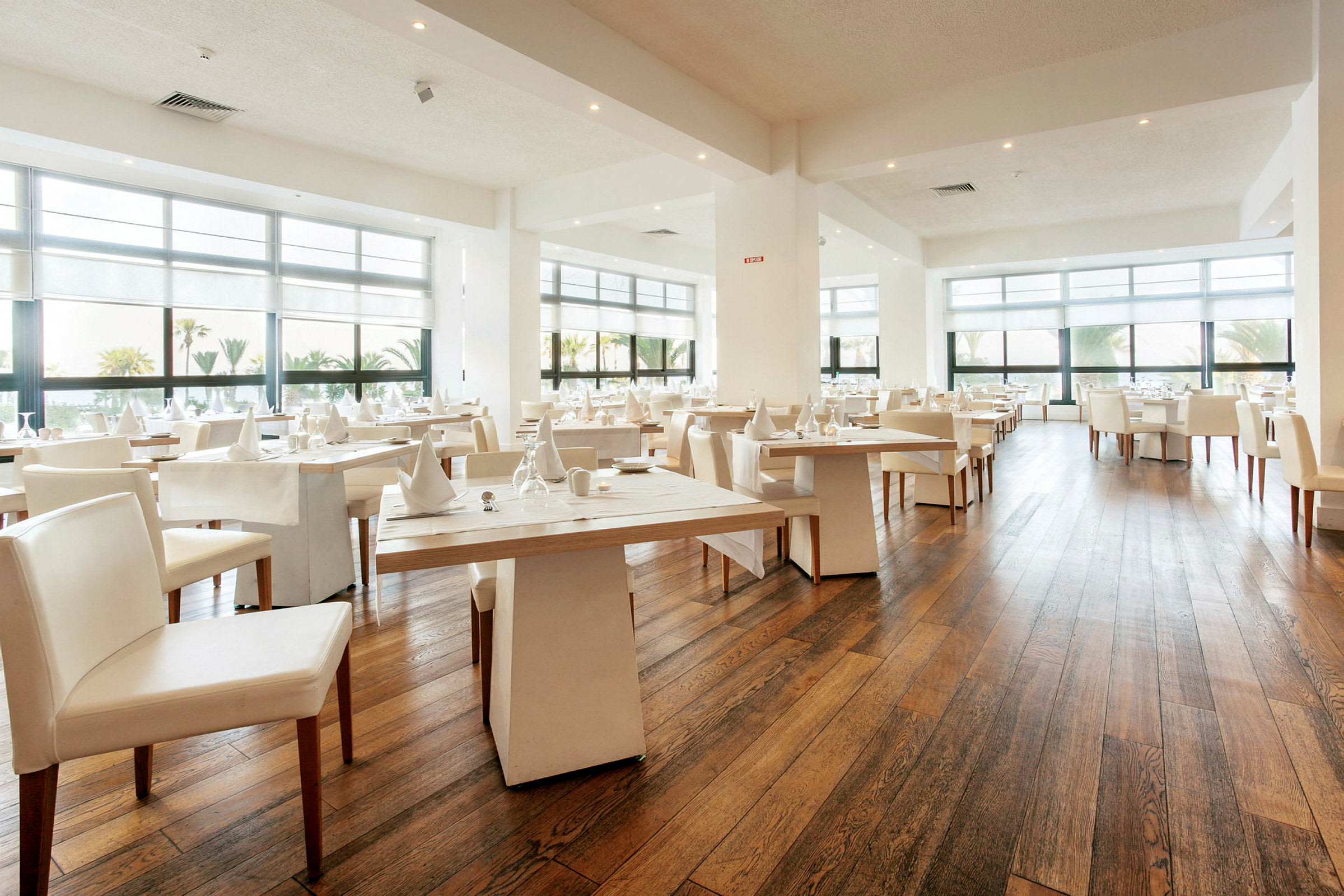En moderne og lys restaurant med store vinduer og dækkede borde. (AI-genereret tekst)