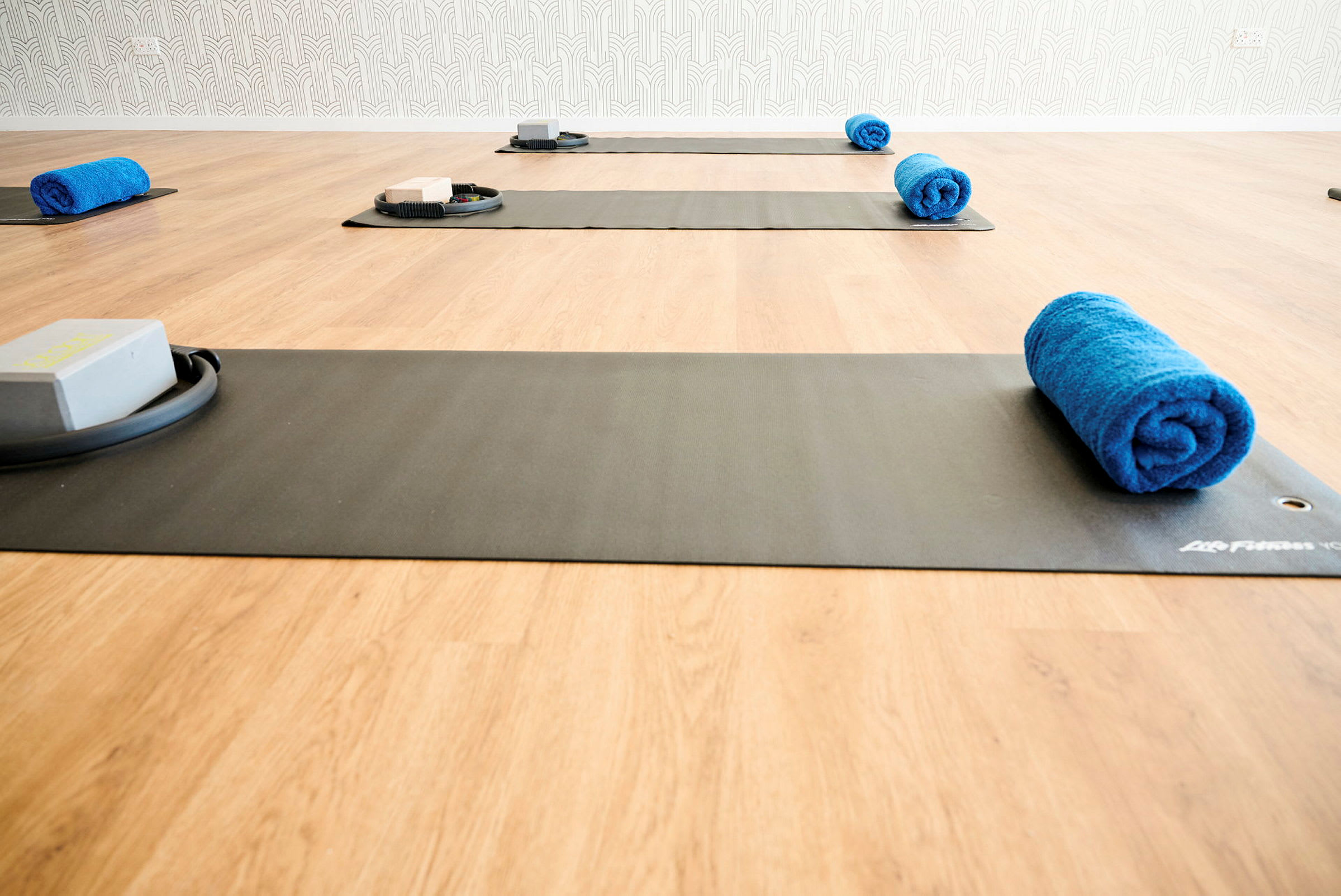 Billede af et træningsstudie med yogamåtter, blå håndklæder og træningsblokke på et trægulv. (AI-genereret tekst)