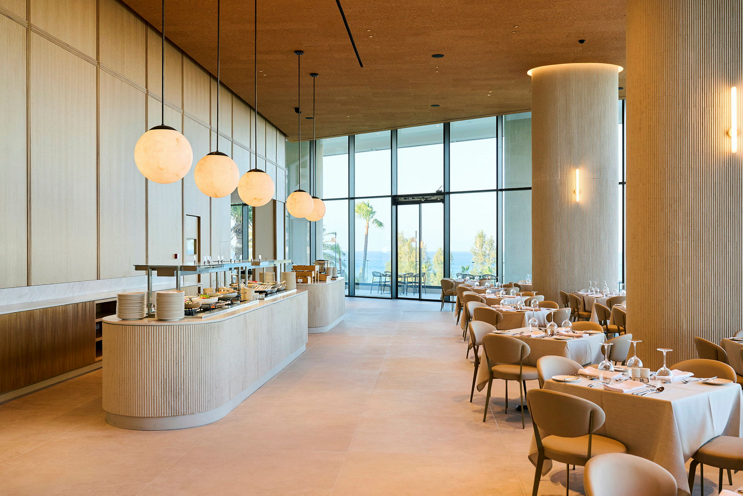 Et moderne og lyst restaurantområde med dækkede borde og store vinduer, der vender ud mod en udendørs udsigt. (AI-genereret tekst)