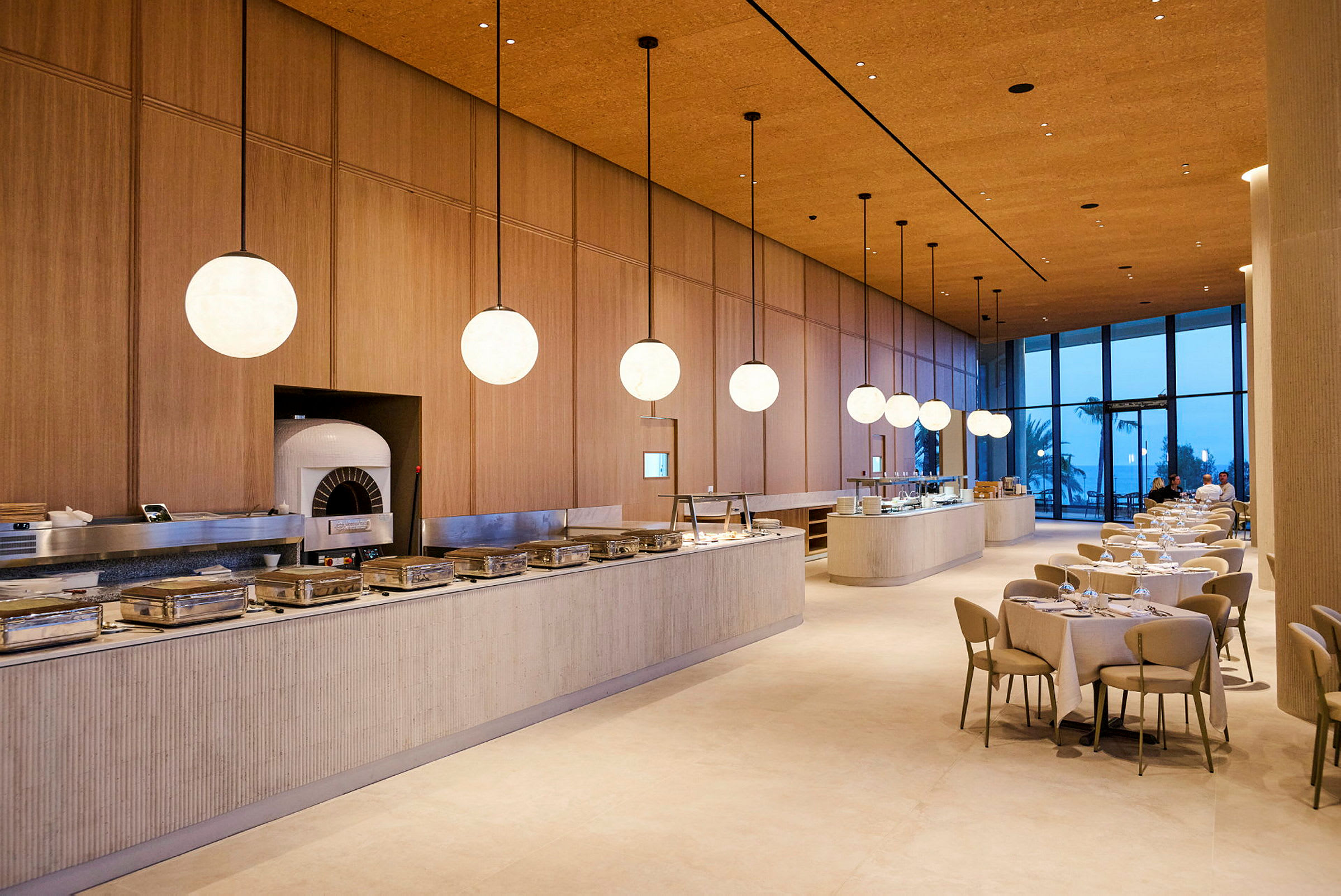 En elegant restaurant med moderne møbler og store vinduer med serveringsborde opstillet. (AI-genereret tekst)