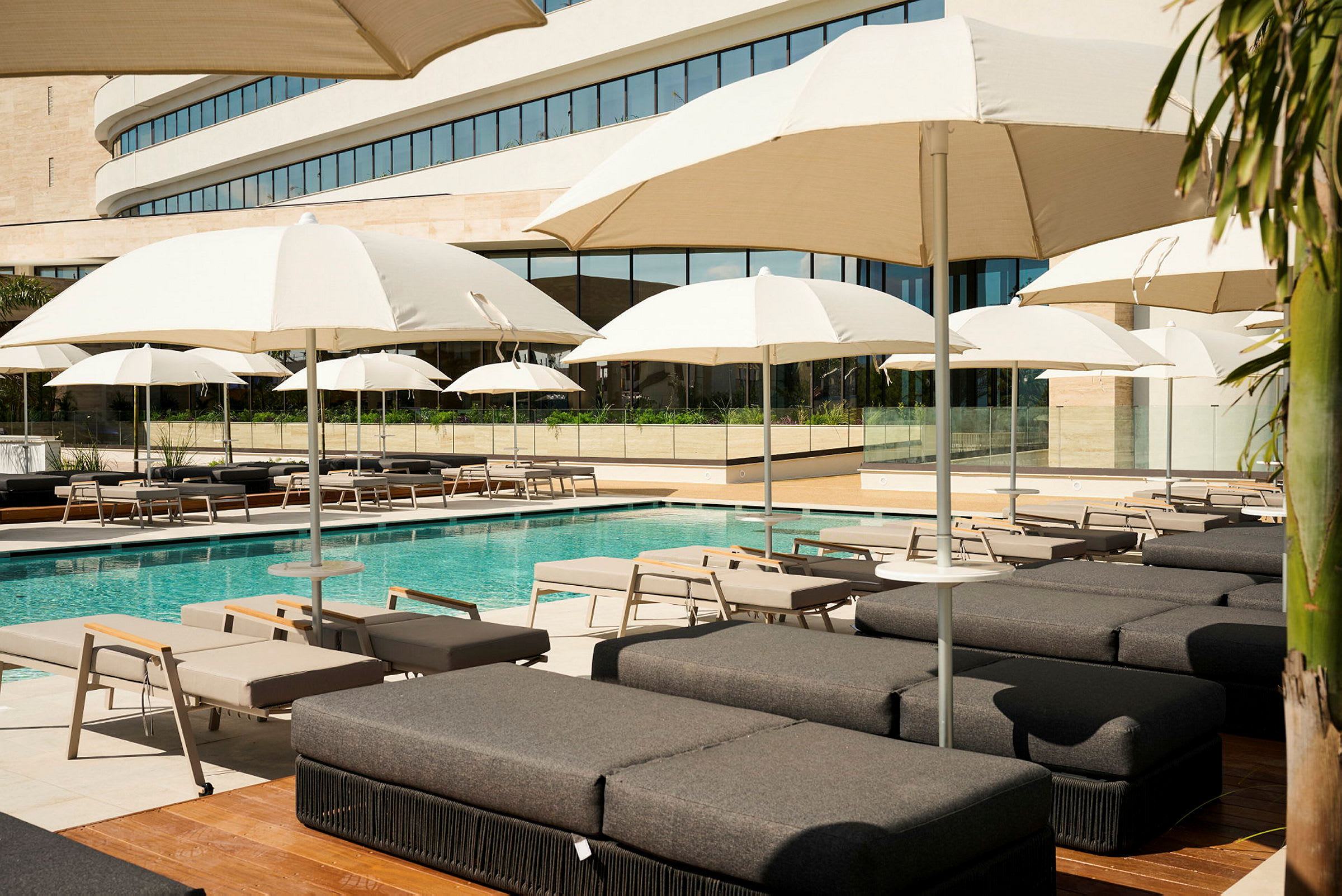 En udendørs swimmingpool med liggestole og hvide parasoller på et hotel. (AI-genereret tekst)