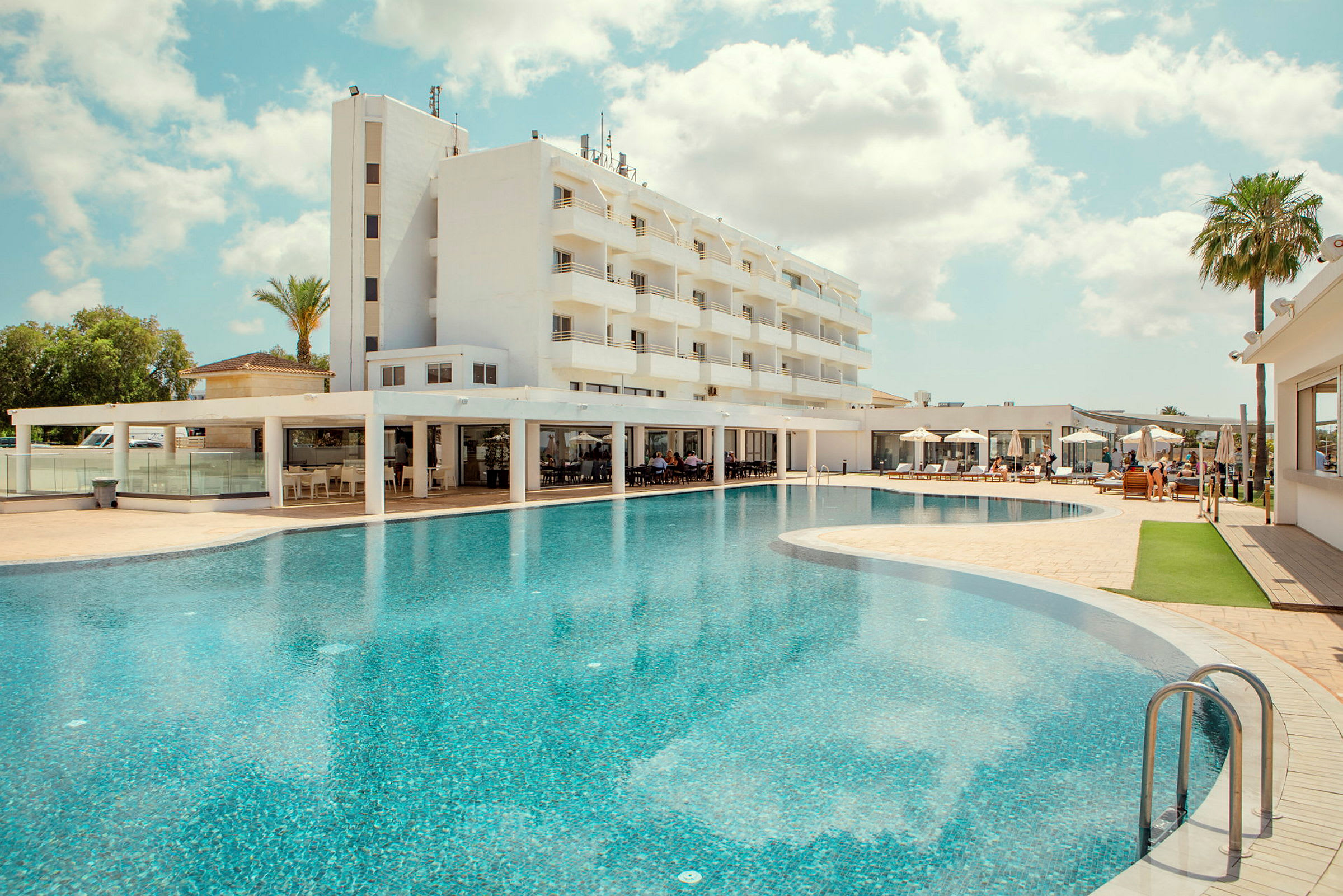 Hotel med en stor pool og liggestole. (AI-genereret tekst)