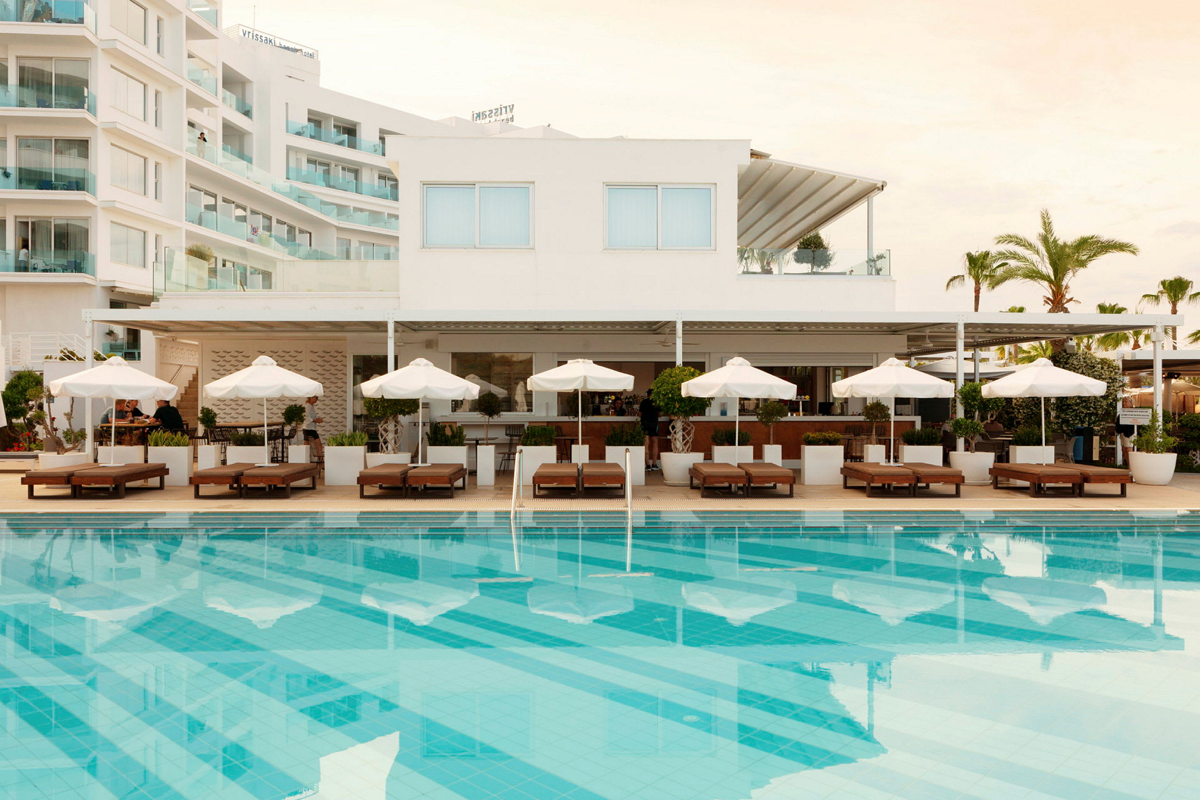 Hotel med pool, liggestole og parasoller. (AI-genereret tekst)