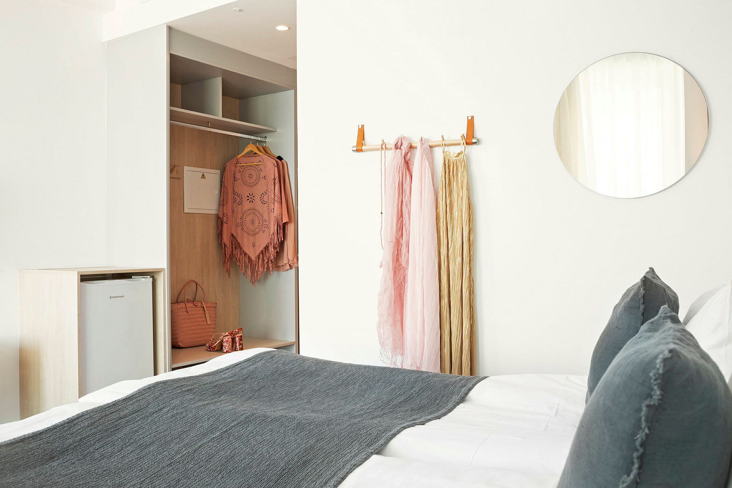 Et hotelværelse med en seng og garderobe; tøj er hængt op. (AI-genereret tekst)