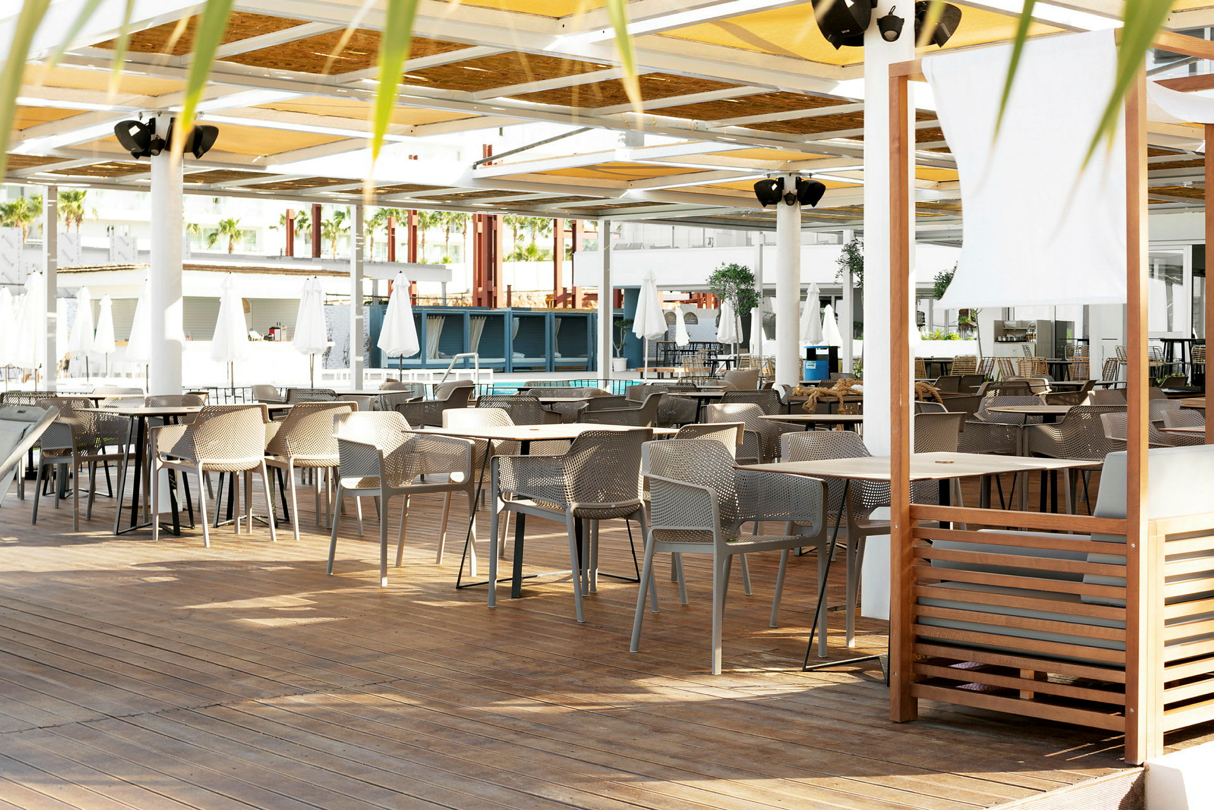 En siddegruppe med borde og stole på en terrasse med tag. (AI-genereret tekst)