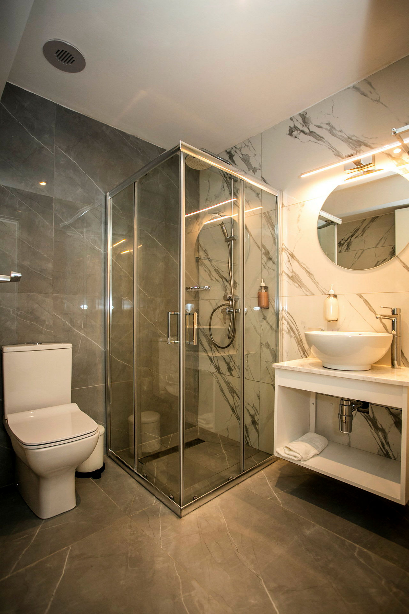 Et moderne badeværelse med brusekabine med glasdøre, toilet og håndvask med spejl over. (AI-genereret tekst)