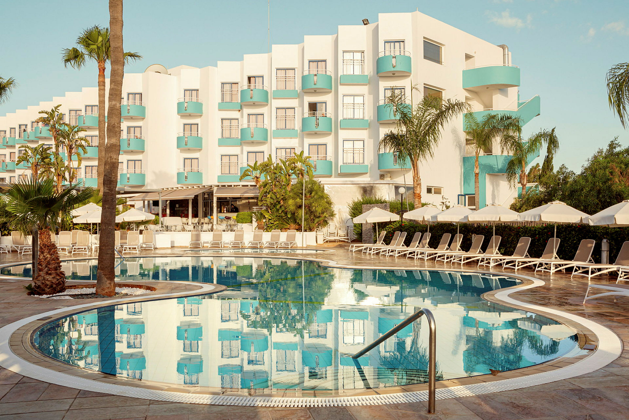 Hotel med moderne design og pool i forgrunden. (AI-genereret tekst)