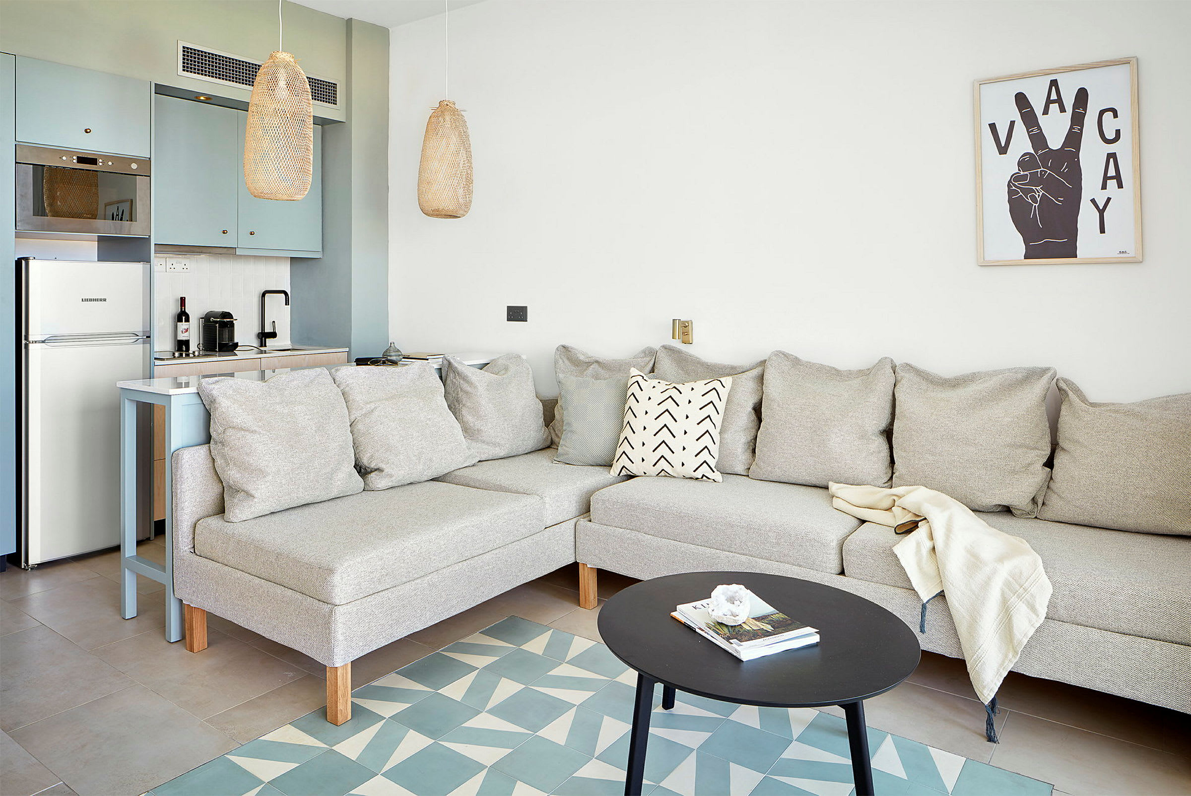 Lyst stueområde med sofa, sofabord og integreret køkken. (AI-genereret tekst)