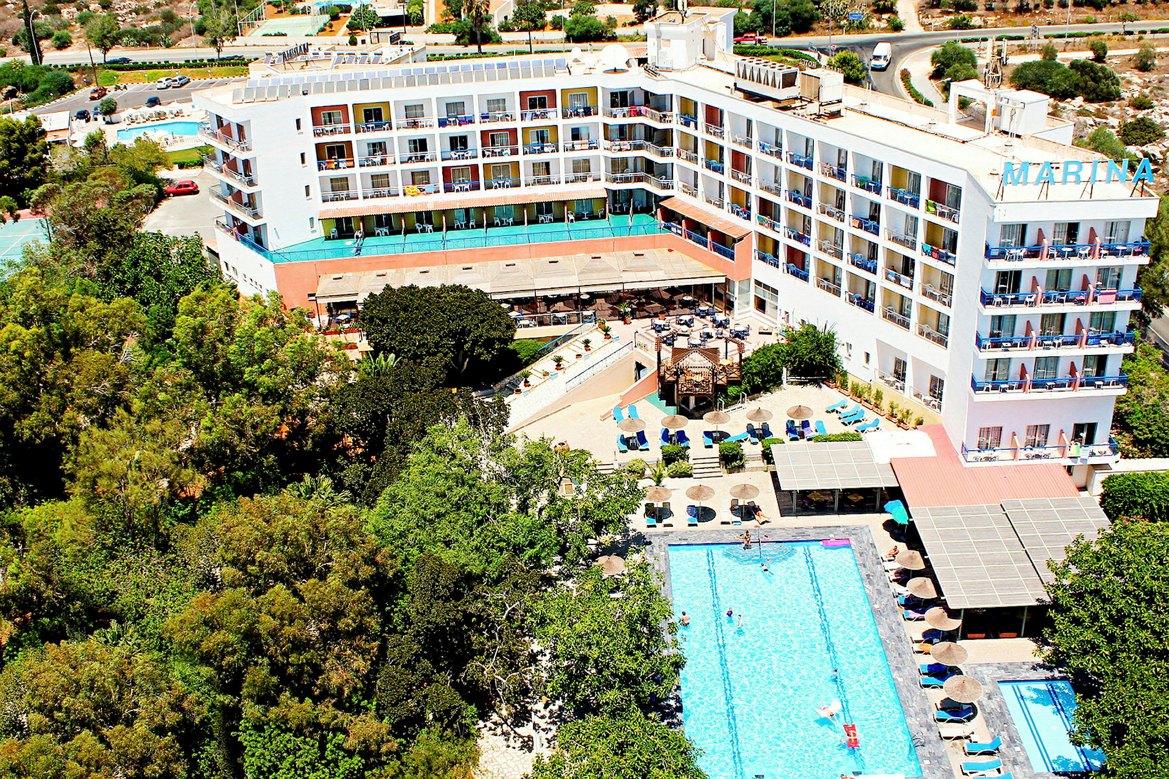 Luftfotografi af hotel med pool og omkringliggende grønt områder. (AI-genereret tekst)