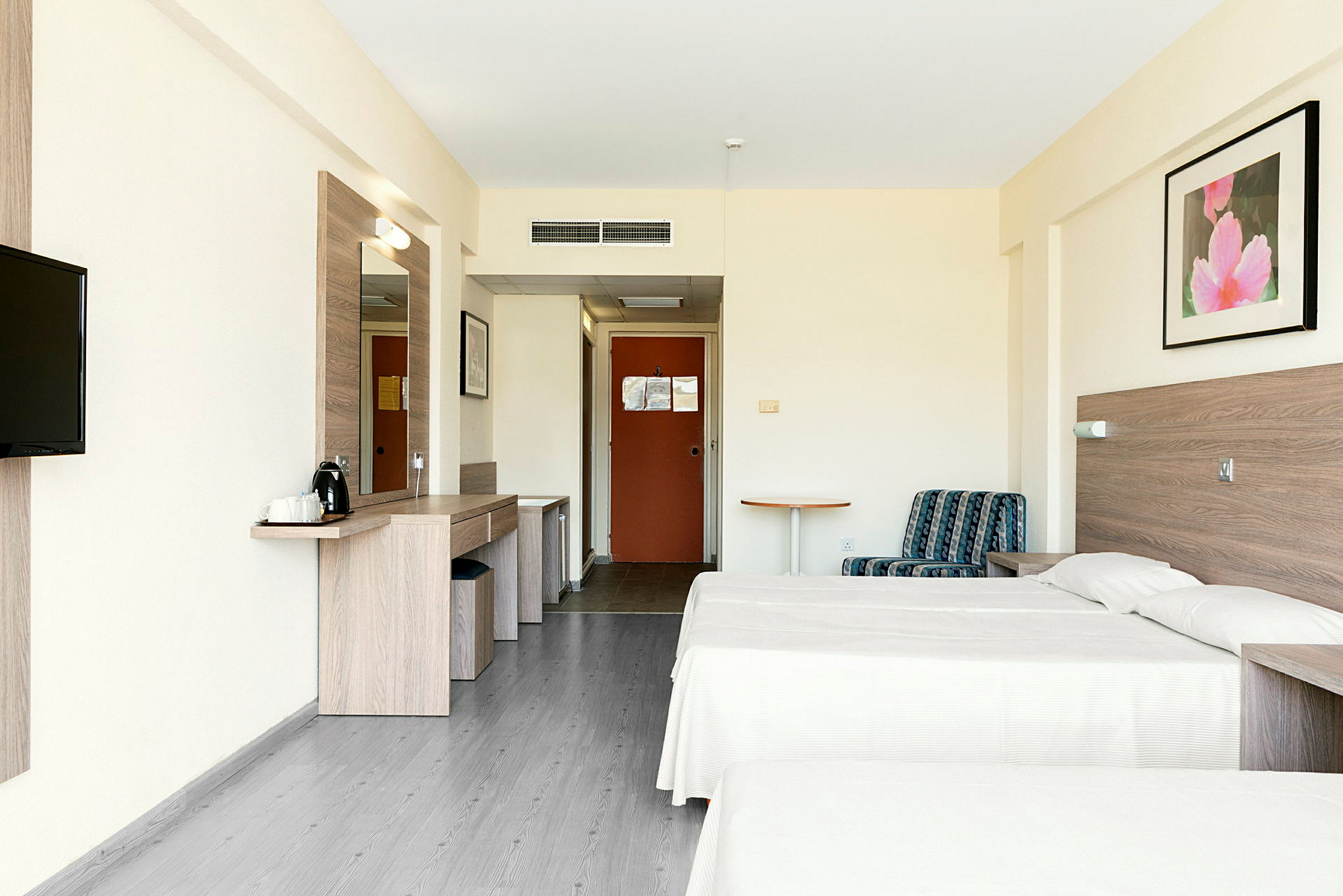 Billedet viser et hotelværelse med to enkeltsenge, en siddeplads og et skrivebord. (AI-genereret tekst)