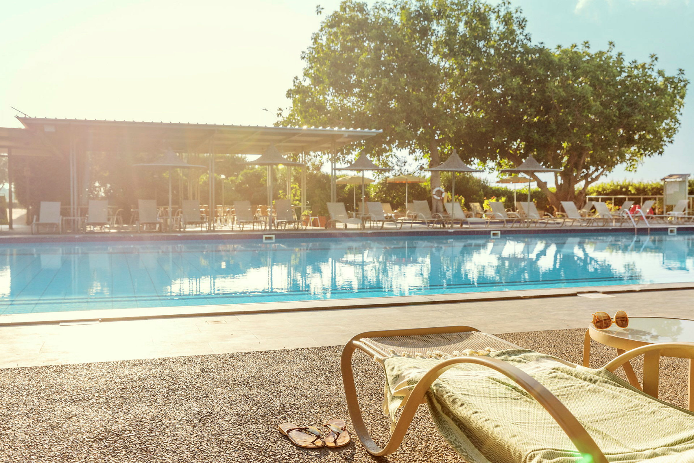 En liggestol og et bord ved kanten af en swimmingpool. (AI-genereret tekst)