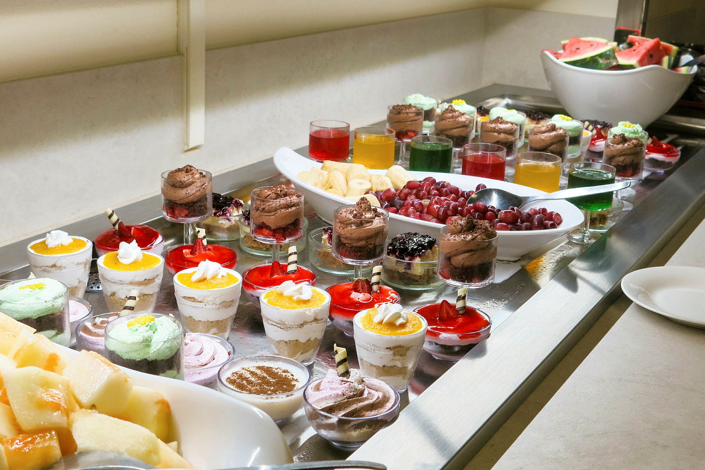 Billede af et dessertbord med forskellige små desserter og frugter. (AI-genereret tekst)