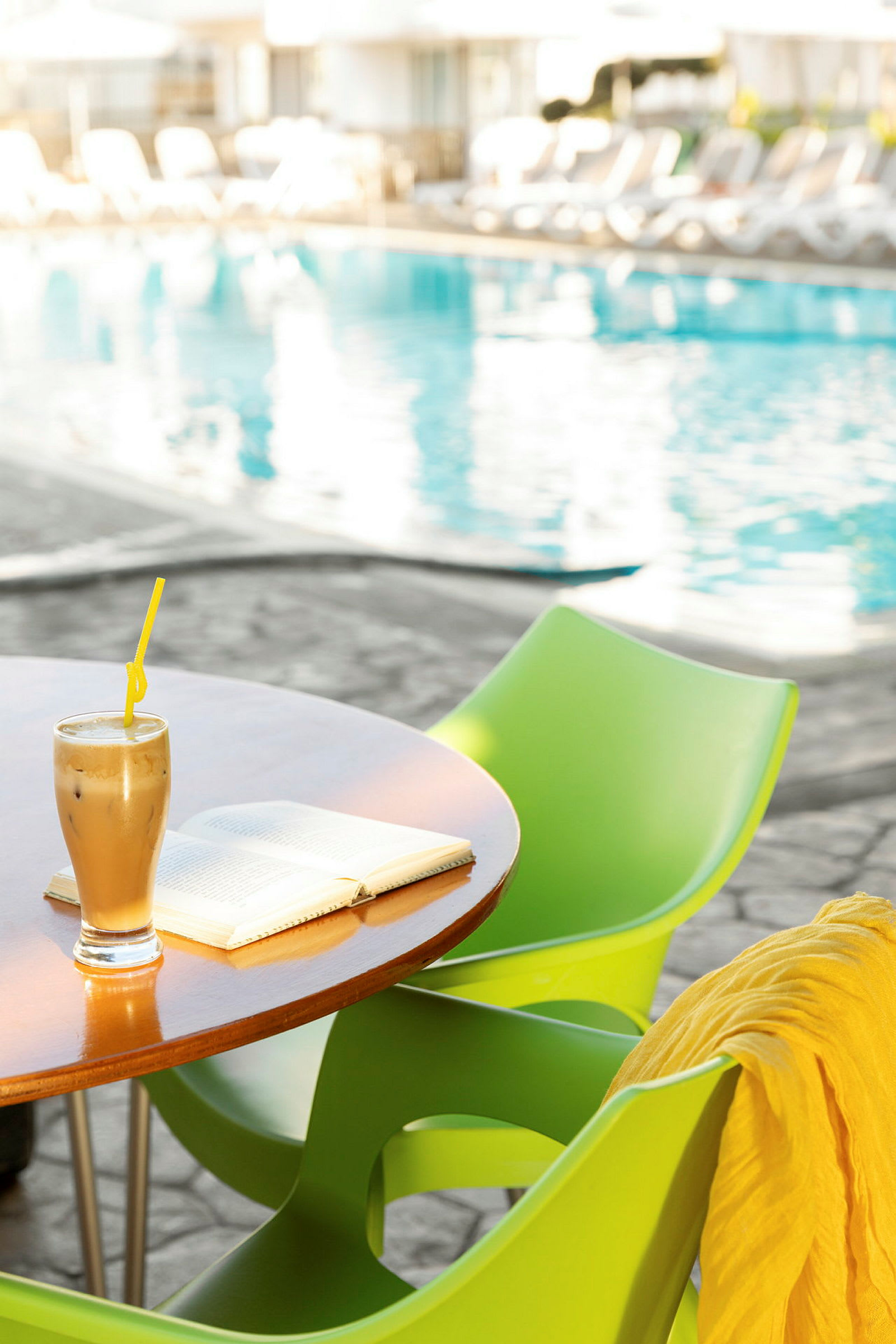 Et bord med en kaffedrik og en bog, ved siden af en pool. (AI-genereret tekst)