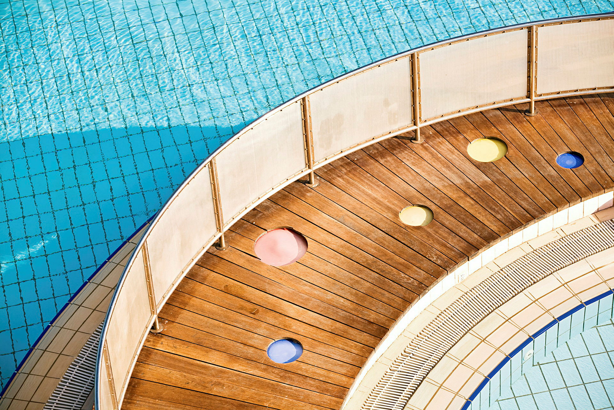 En træbro med farvede huller nær en swimmingpool. (AI-genereret tekst)