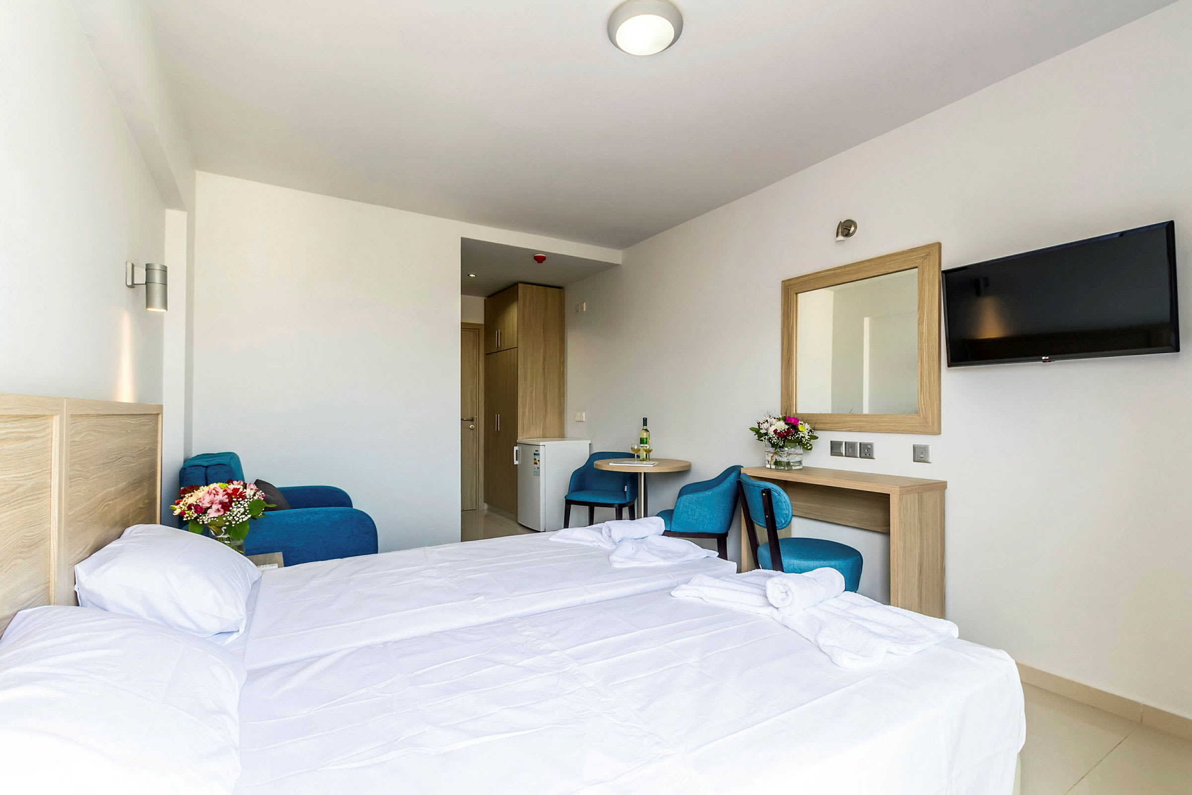 Hotelværelse med seng, bord, stol, spejl og TV. (AI-genereret tekst)
